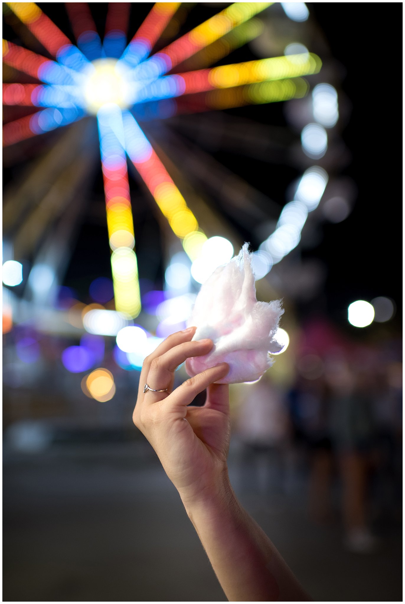 Girl holds up cotton candy in front of Ferris Wheel during carnival engagement session in Utah | Jessie and Dallin Photography | Utah Wedding Photographers