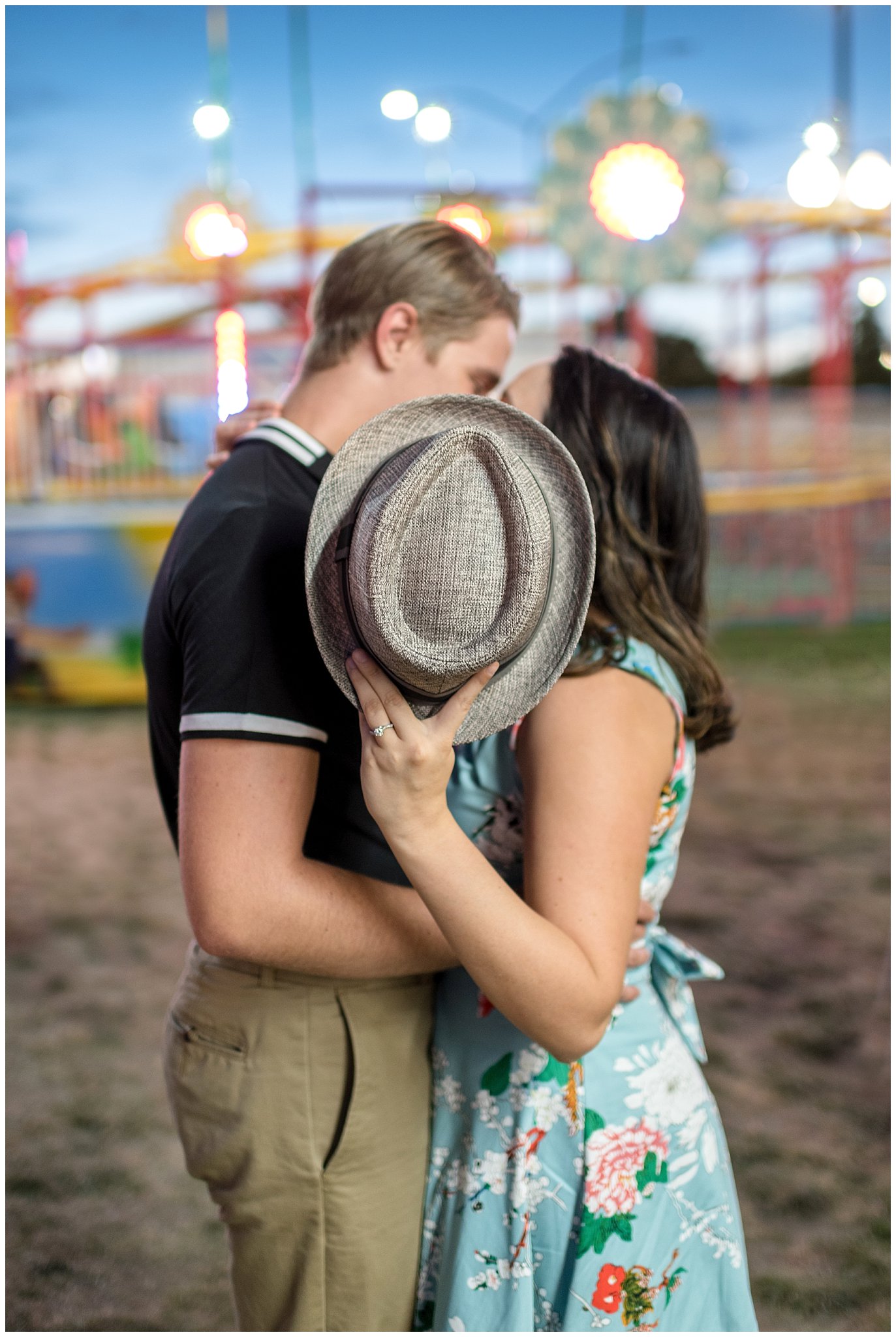 Couple kisses behind fedora hat during their carnival engagement session at the state fair in Utah | Jessie and Dallin Photography | Utah Wedding Photographers