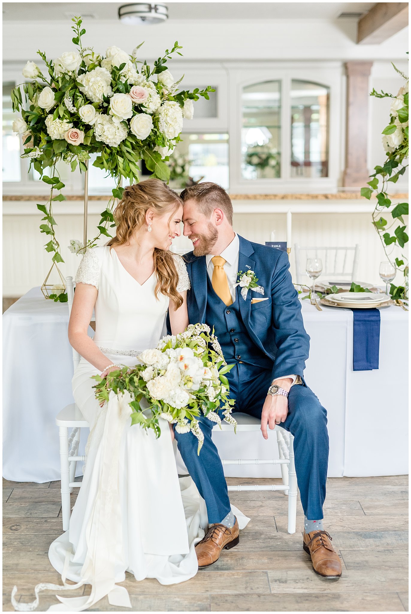 Bride and groom snuggling on chairs | Navy, white and gold wedding | Talia Event Center