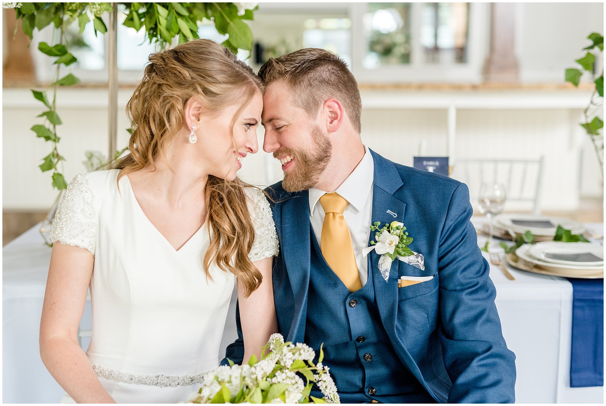 Bride and groom snuggling and smiling on chairs | Navy, white and gold wedding | Talia Event Center