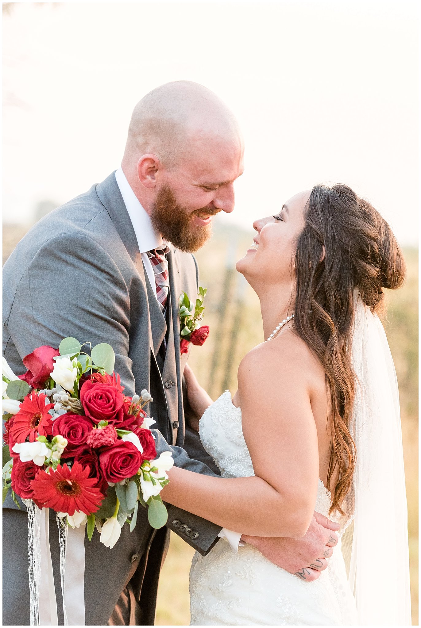 Bride and groom candidly smiling and laughing during sunset portraits | Red and Grey wedding | Davis County Outdoor Wedding | Jessie and Dallin Photography