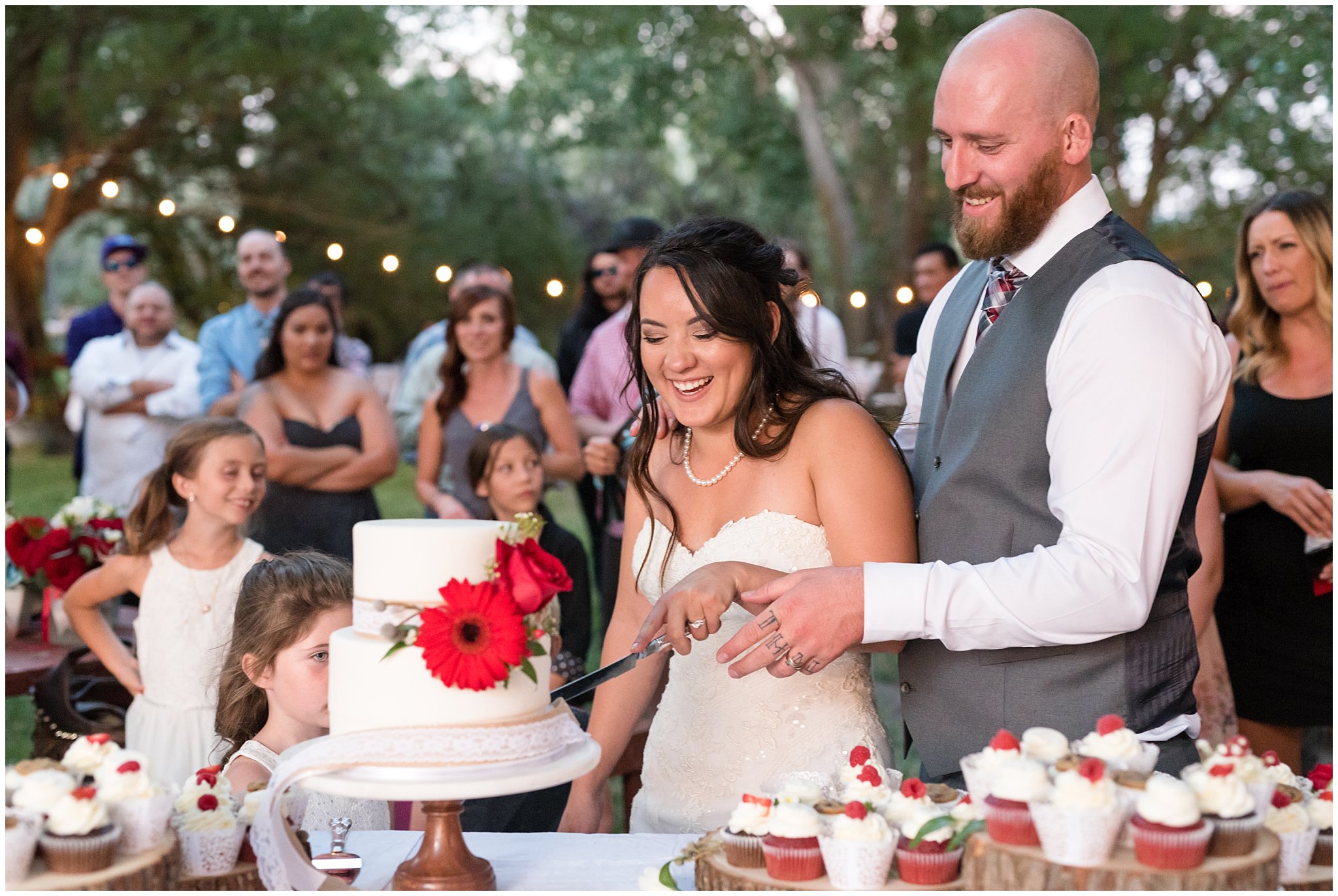 Bride and groom laughing while cutting the cake | Red and Grey wedding | Davis County Outdoor Wedding | Jessie and Dallin Photography