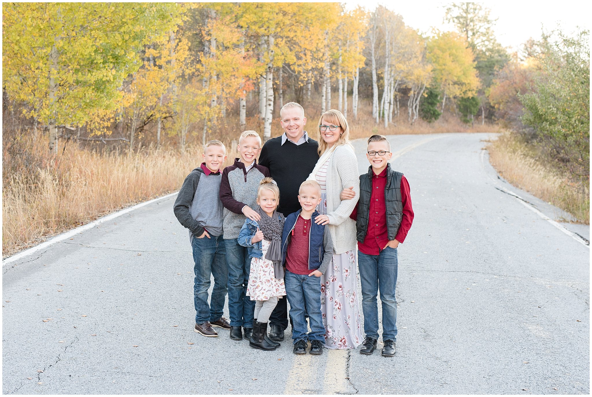 Family smiling on the road with aspen trees in the mountains | Fall Family Pictures in the Mountains | Snowbasin, Utah | Jessie and Dallin Photography