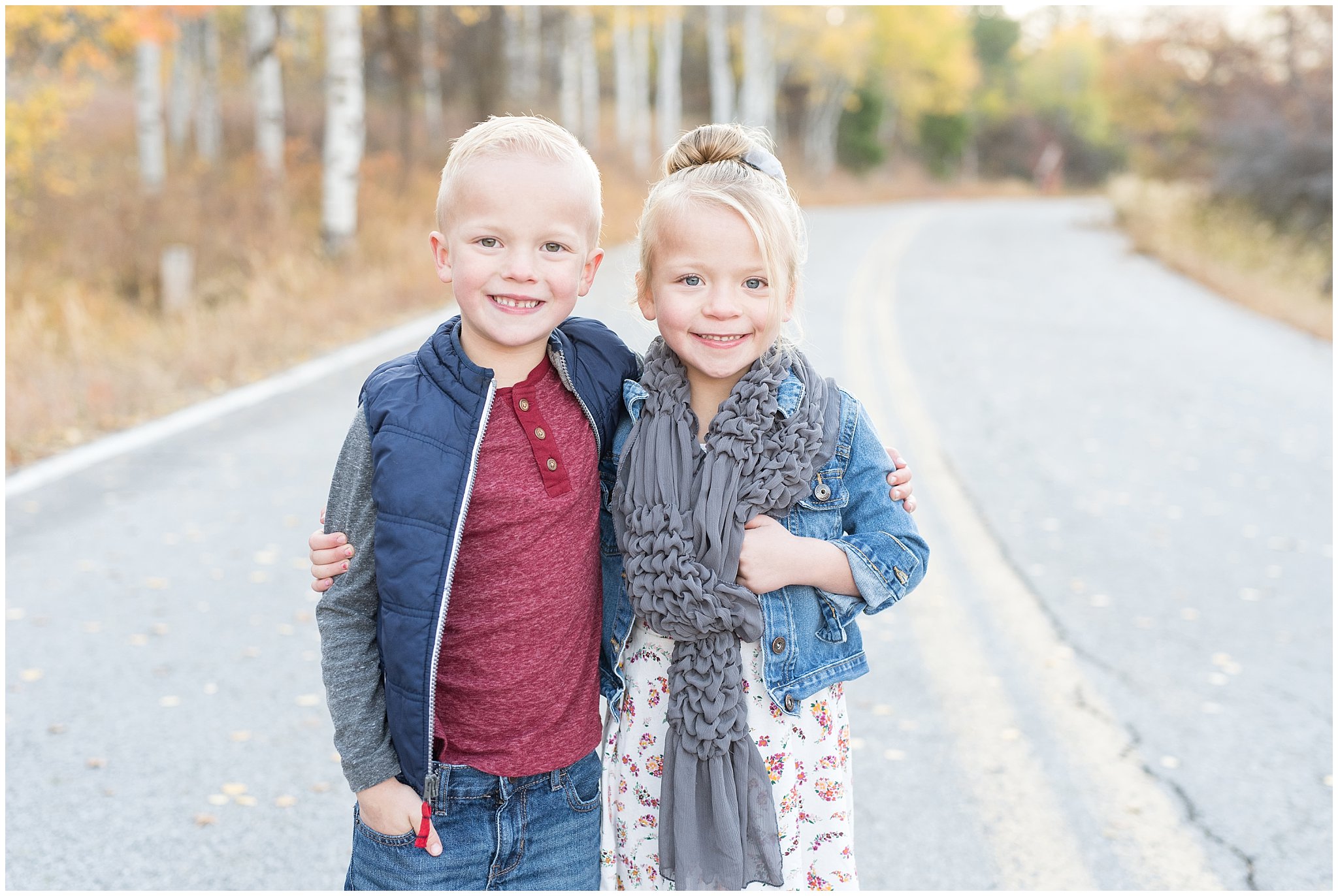 Young twin brother and sister smiling at the camera during fall pictures | Fall Family Pictures in the Mountains | Snowbasin, Utah | Jessie and Dallin Photography