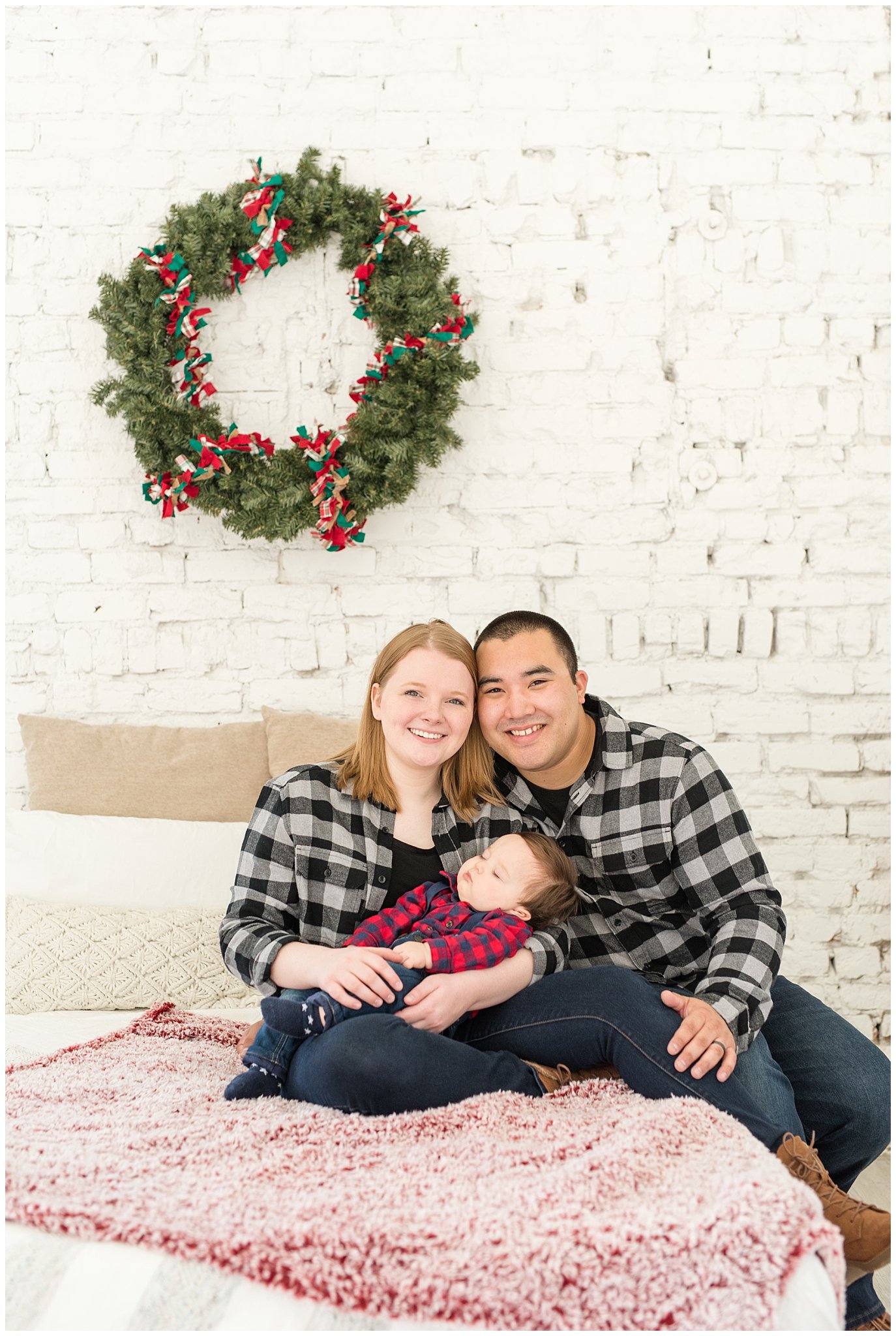 Parents sit on bed with baby boy while he sleeps | Family Christmas session at the 5th floor | Utah Photographers | Jessie and Dallin Photography