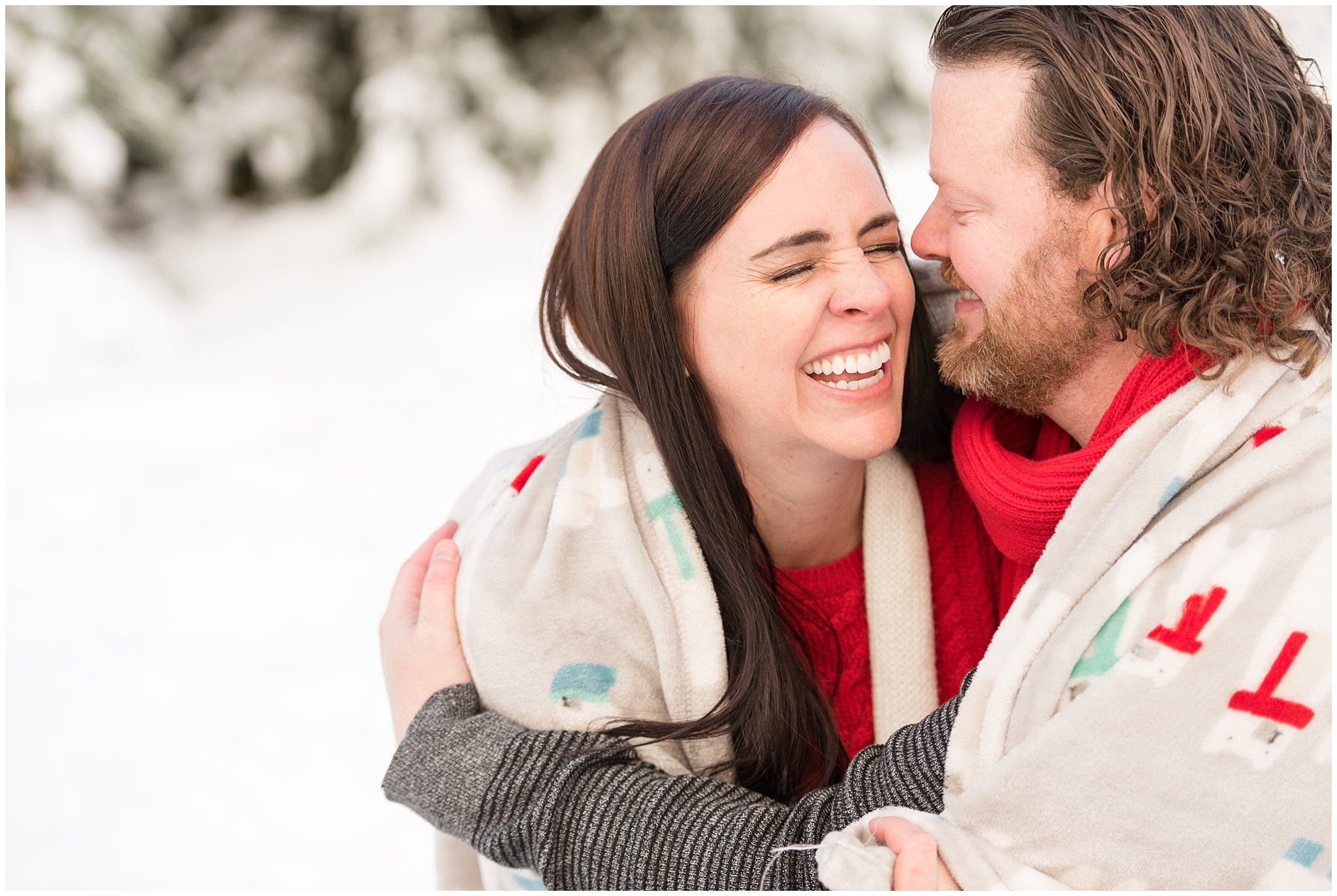 Couple snuggling and laughing with a blanket in the snow | Utah Family Christmas Photoshoot | Oak Hills Reception and Event | Jessie and Dallin Photography