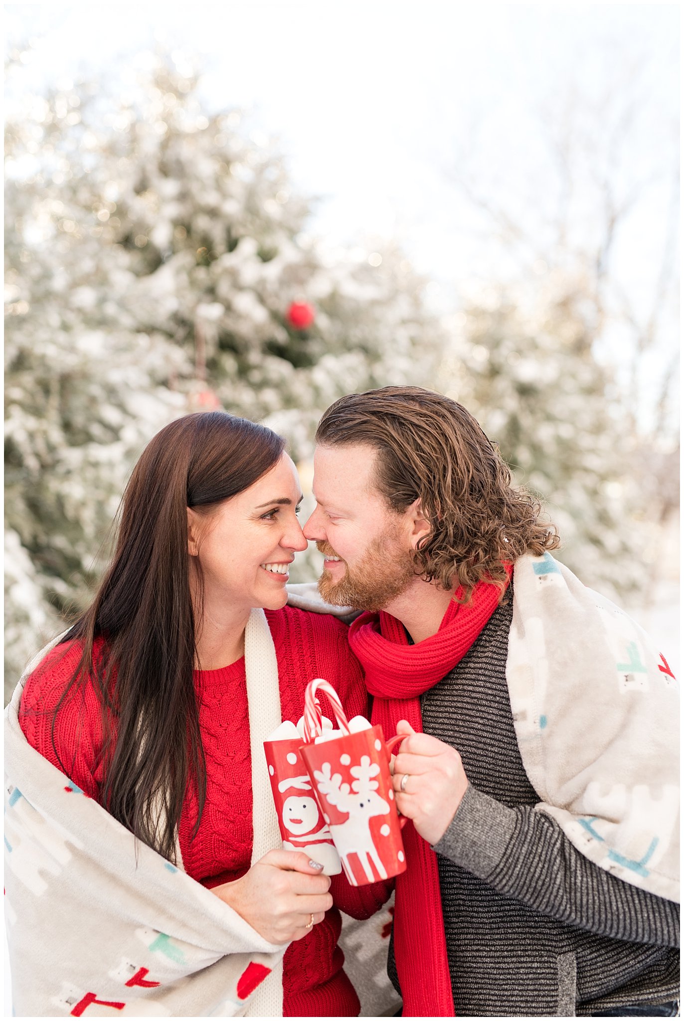 Couple with hot chocolate and a blanket in the snow in front of Christmas trees | Utah Family Christmas Photoshoot | Oak Hills Reception and Event | Jessie and Dallin Photography