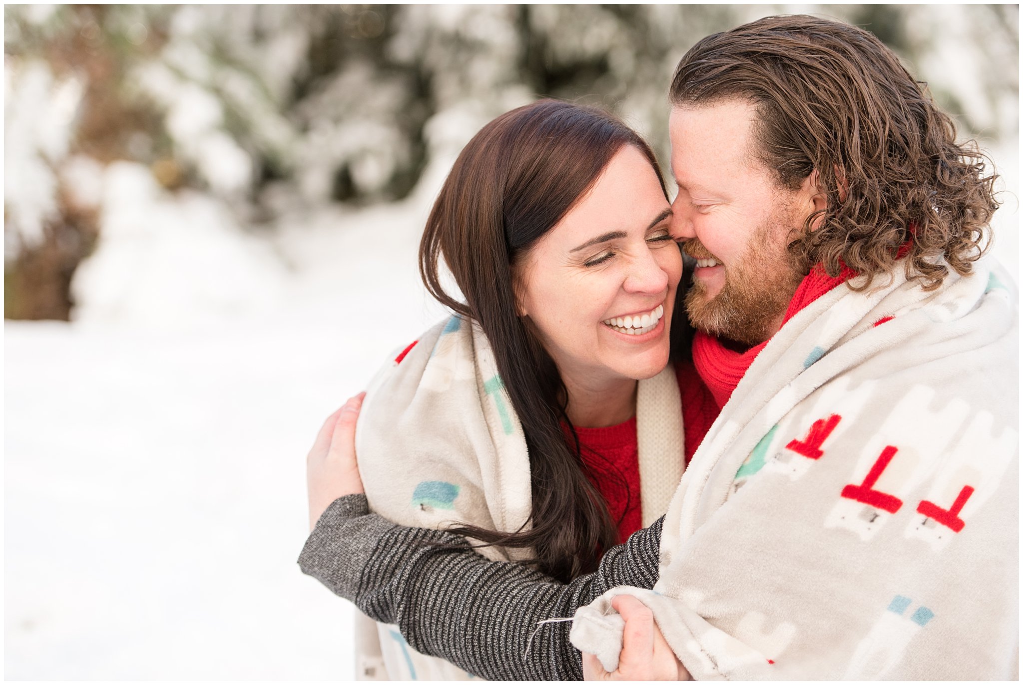 Couple cuddled in blanket and laughing in the snow | Utah Family Christmas Photoshoot | Oak Hills Reception and Event | Jessie and Dallin Photography