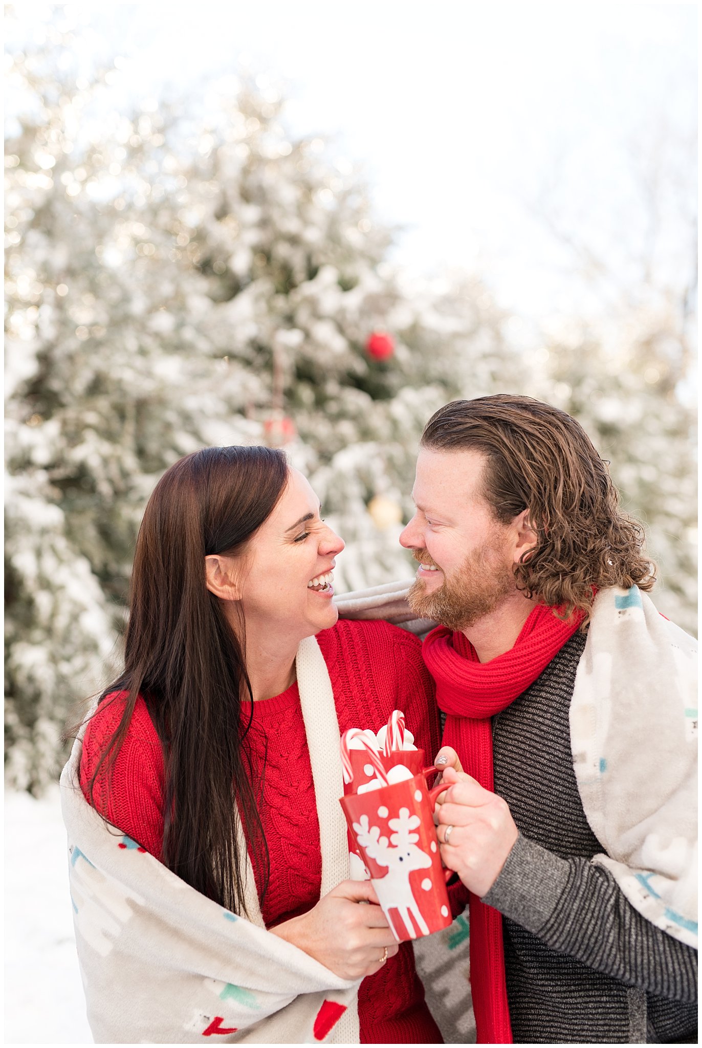Couple cuddling and laughing with hot chocolate mugs in the snow | Utah Family Christmas Photoshoot | Oak Hills Reception and Event | Jessie and Dallin Photography