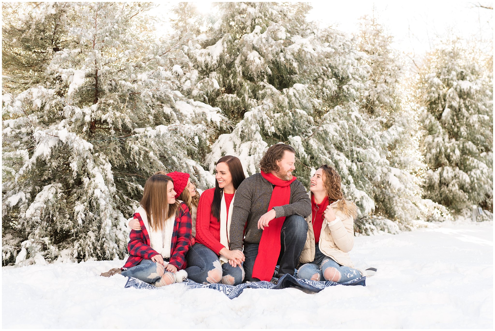 Family looking and laughing in the snow in front of Christmas trees | Utah Family Christmas Photoshoot | Oak Hills Reception and Event | Jessie and Dallin Photography