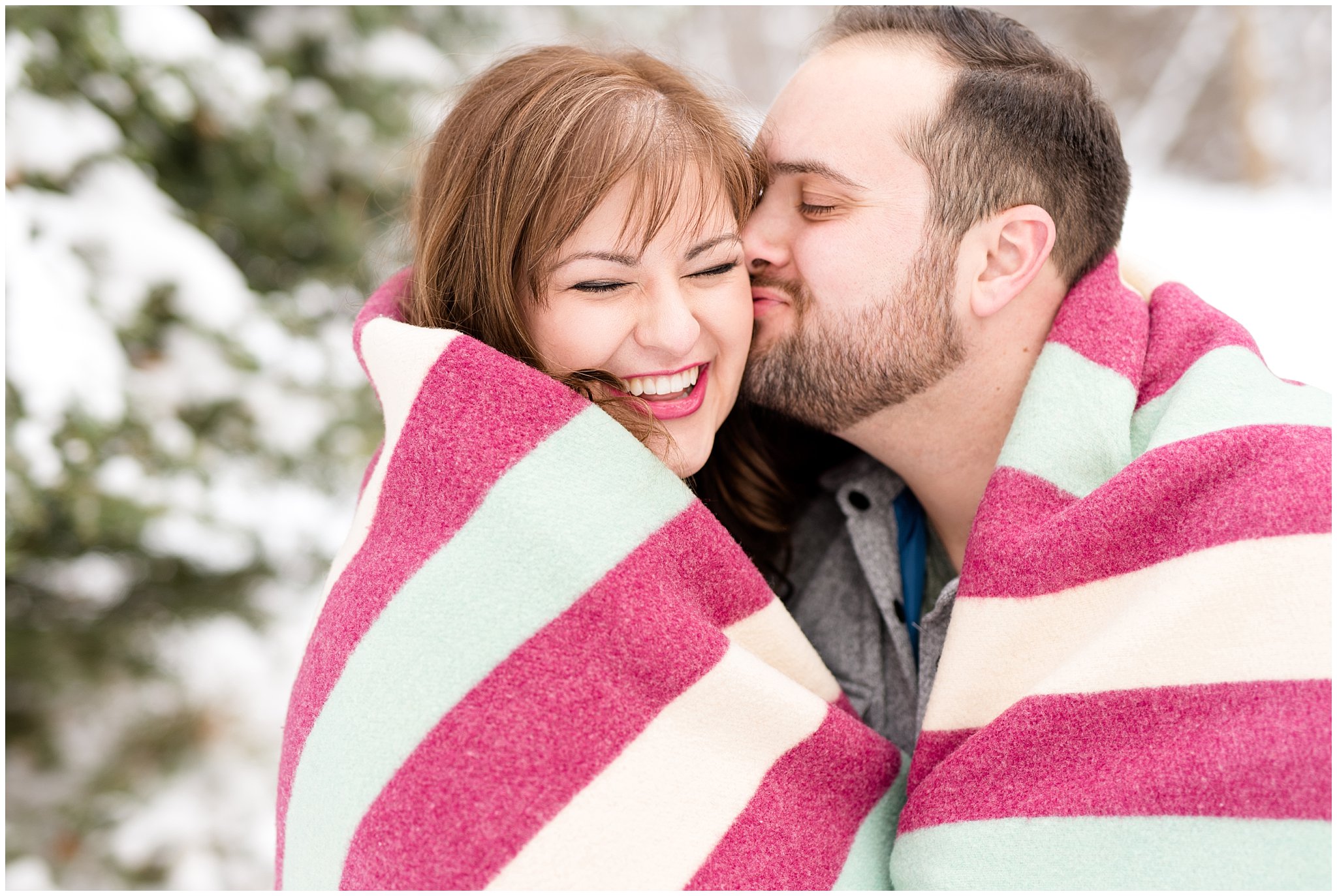 Guy kisses girl on the cheeks while in wrapped in a blanket outdoors | Winter Engagement at Mueller Park and the Utah State Capitol | Jessie and Dallin Photography
