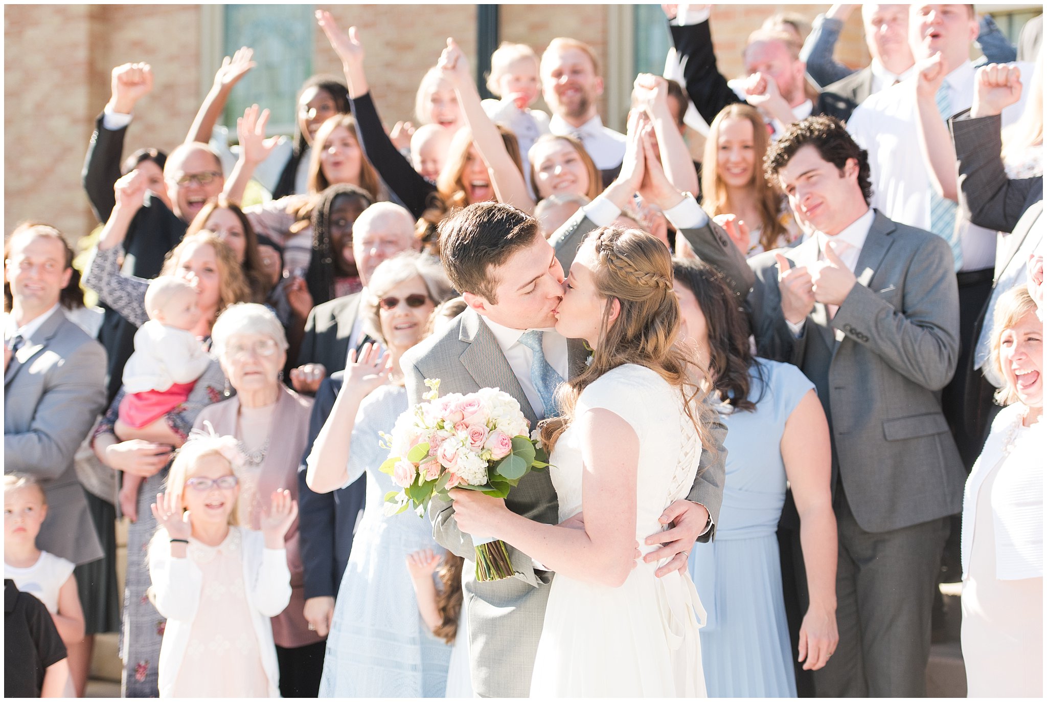 Bride and groom kiss in front of family at Provo City Center temple with grey, blush, and light blue wedding colors | Spring Provo City Center Temple Wedding | Utah Wedding Photographers | Jessie and Dallin Photography