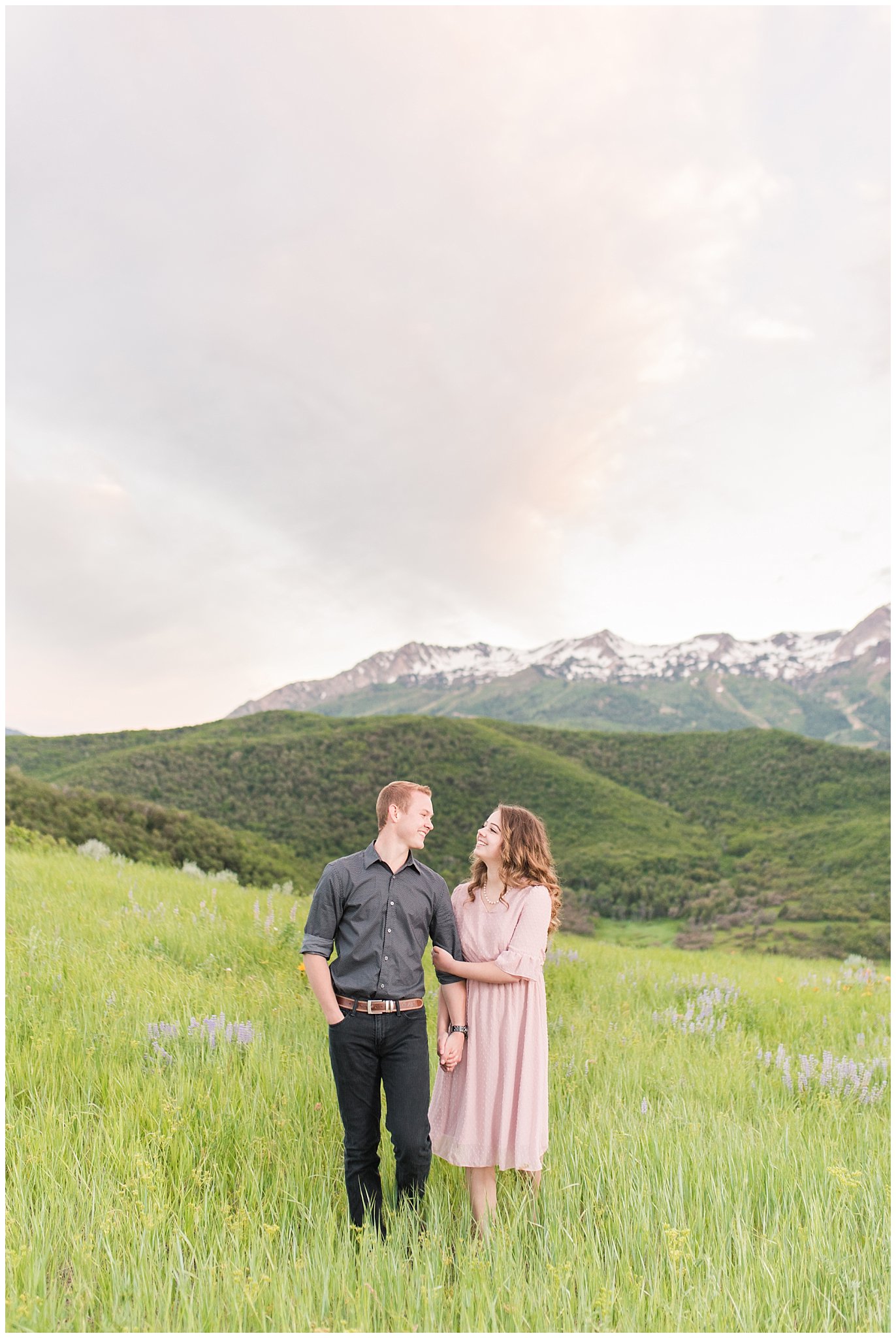 Couple in blush dress and grey and black buttoned shirt in front of a mountain view | Trapper's Loop Mountain Engagement | Utah Mountain Engagement Session | Jessie and Dallin Photography
