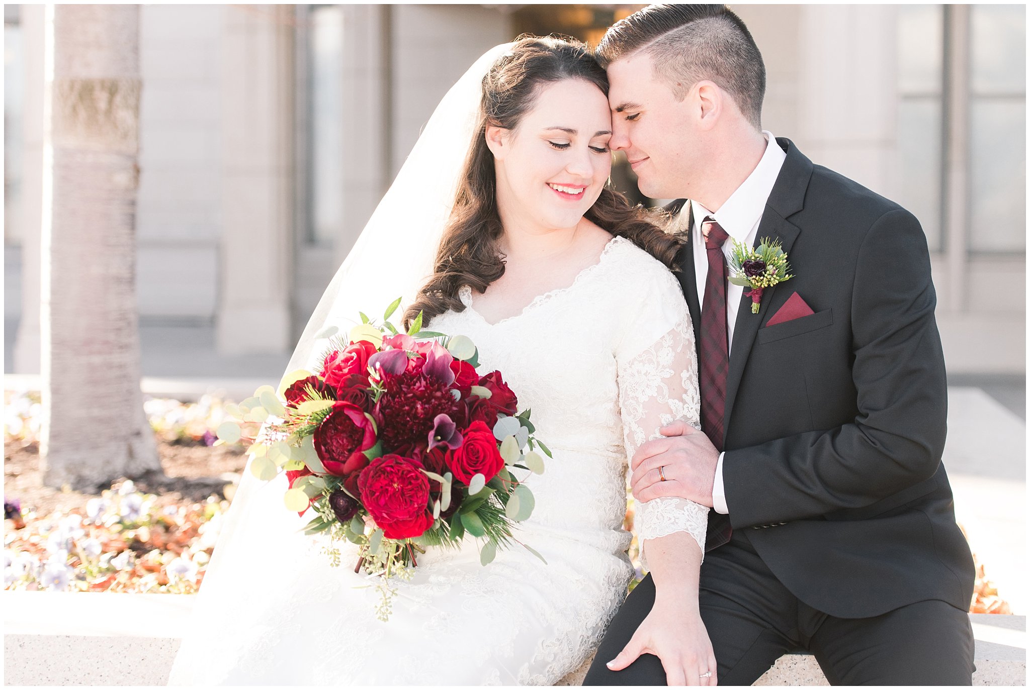 Bride and groom portraits with a veil, flowy lace dress and black suit with red and white bouquet at the Oquirrh Mountain Temple | Oquirrh Mountain Temple and Gardner Village Wedding | The Gathering Place | Jessie and Dallin Photography