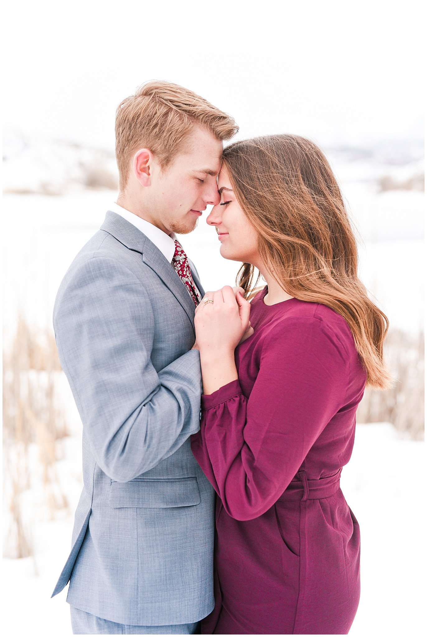 Couple dressed up in wine colored dress and light blue suit in the snowy Utah mountains | Mountain Green Winter Engagement | Jessie and Dallin Photography