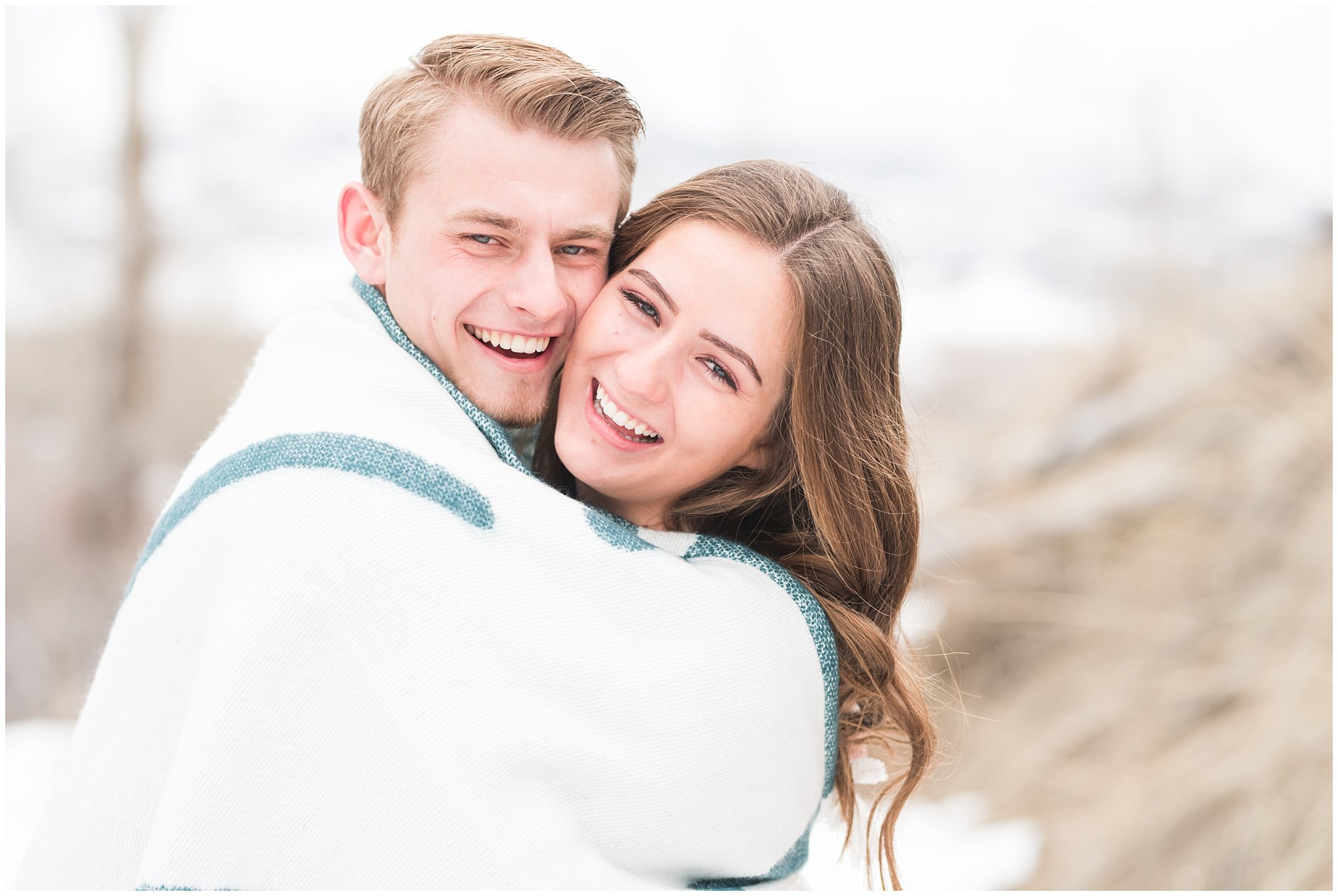 Couple dressed in black dress, grey sweater, and blanket in the snowy Utah mountains | Mountain Green Winter Engagement | Jessie and Dallin Photography