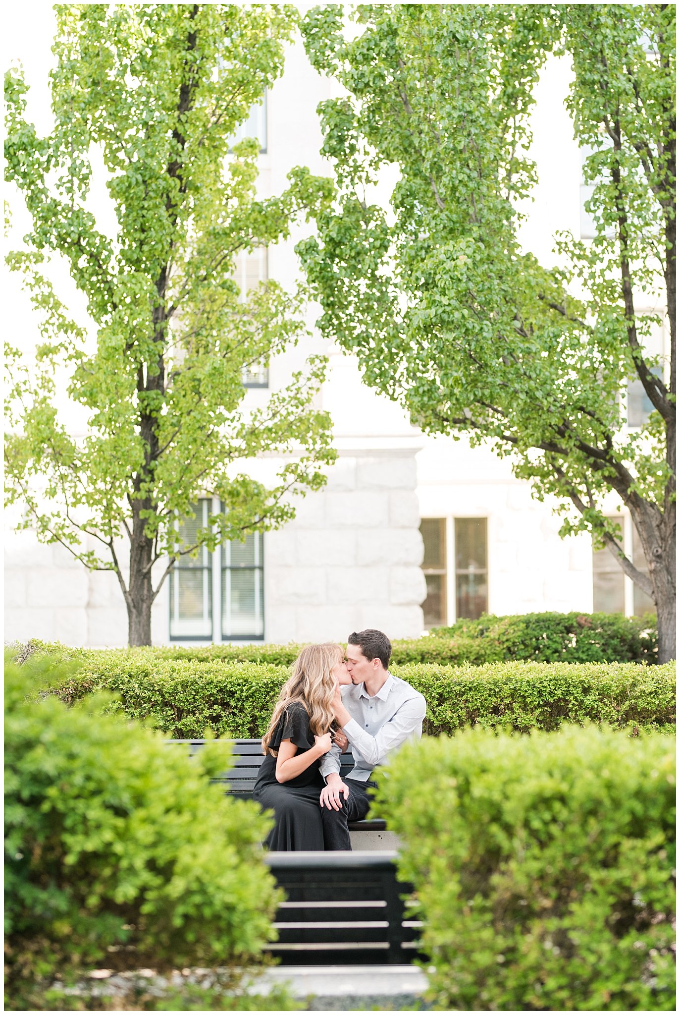 Couple in black dress and grey button up shirt in the green trees at the Utah State Capitol | Utah State Capitol and Tunnel Springs Engagement Session | Jessie and Dallin Photography