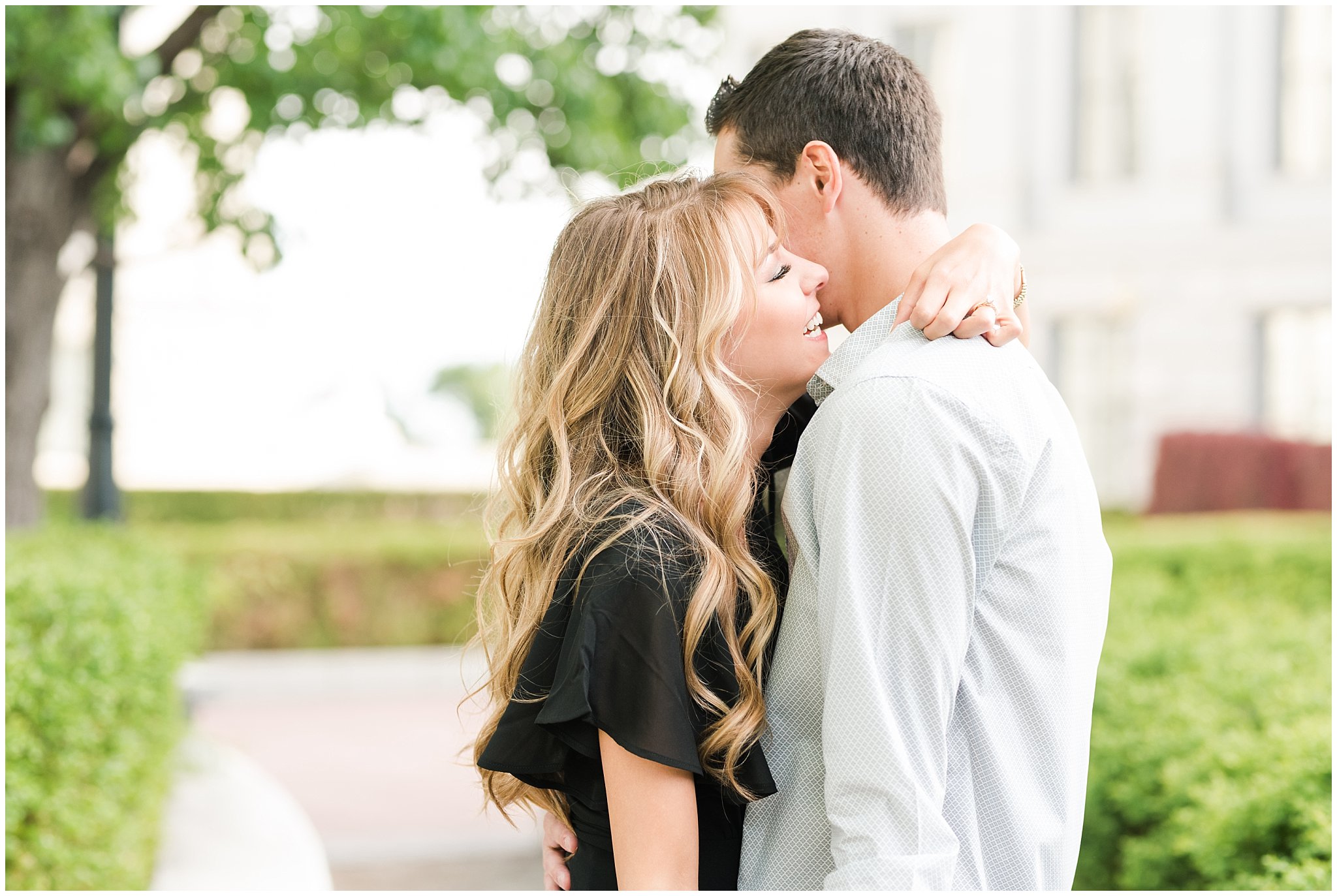 Couple in black dress and grey button up shirt in the green trees at the Utah State Capitol | Utah State Capitol and Tunnel Springs Engagement Session | Jessie and Dallin Photography