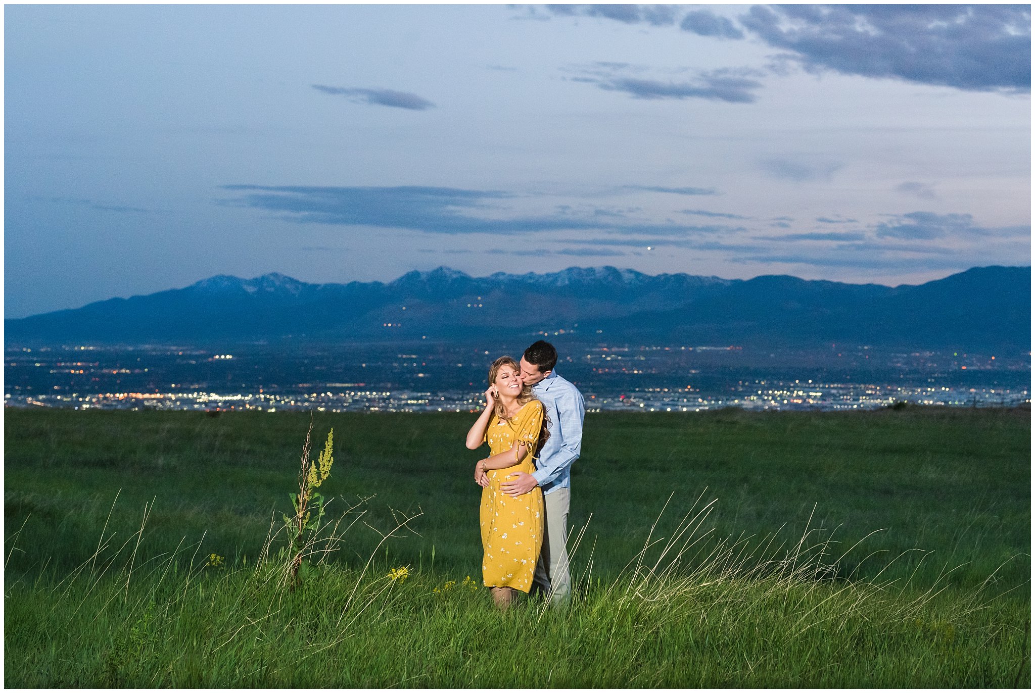 Couple on a mountain side at sunset with Salt Lake City lights behind them | Utah State Capitol and Tunnel Springs Engagement Session | Jessie and Dallin Photography