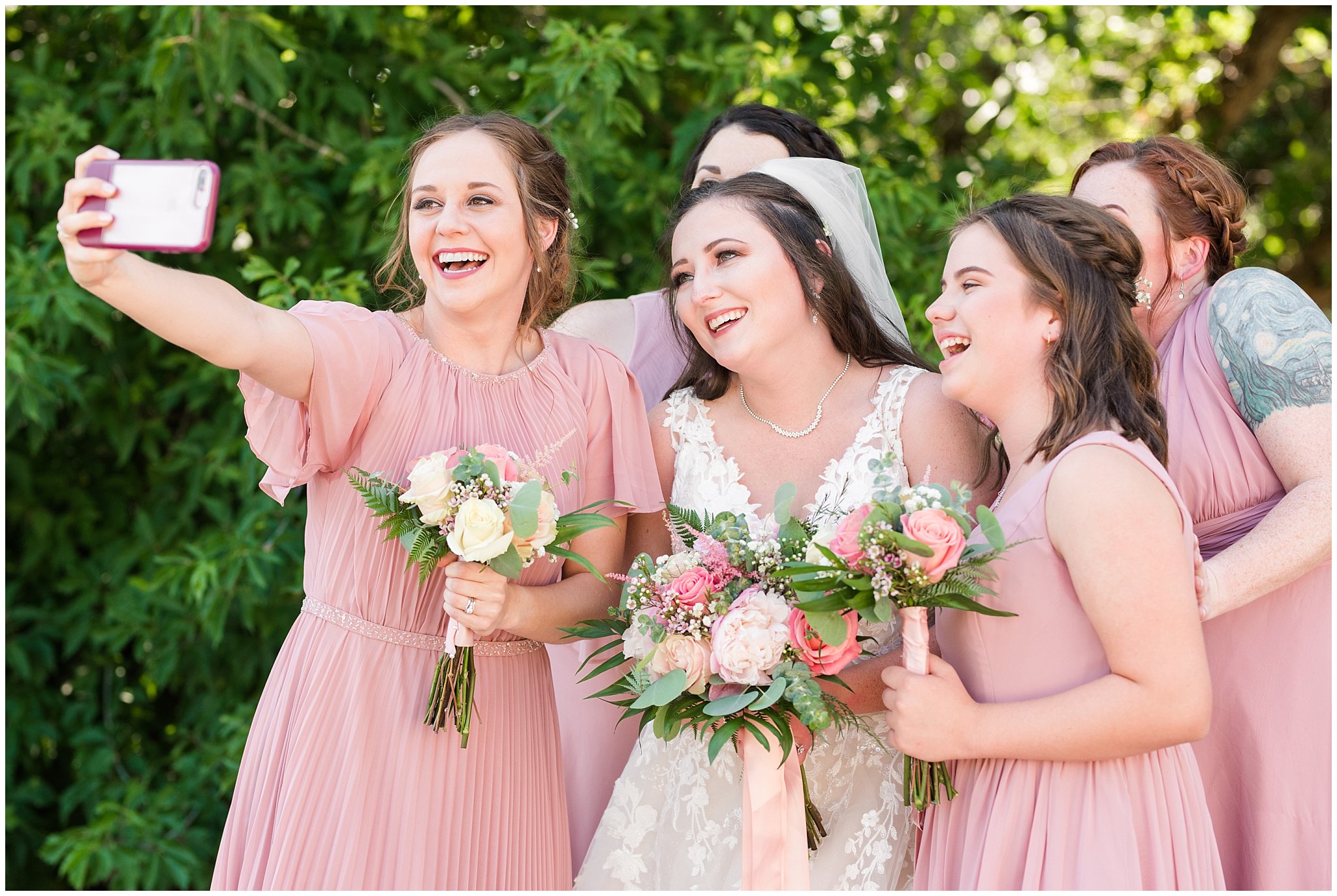 Bride and bridesmaids take selfie in blush dusty rose dresses with green white and blush florals | Oak Hills Utah Dusty Rose and Gray Summer Wedding | Jessie and Dallin Photography