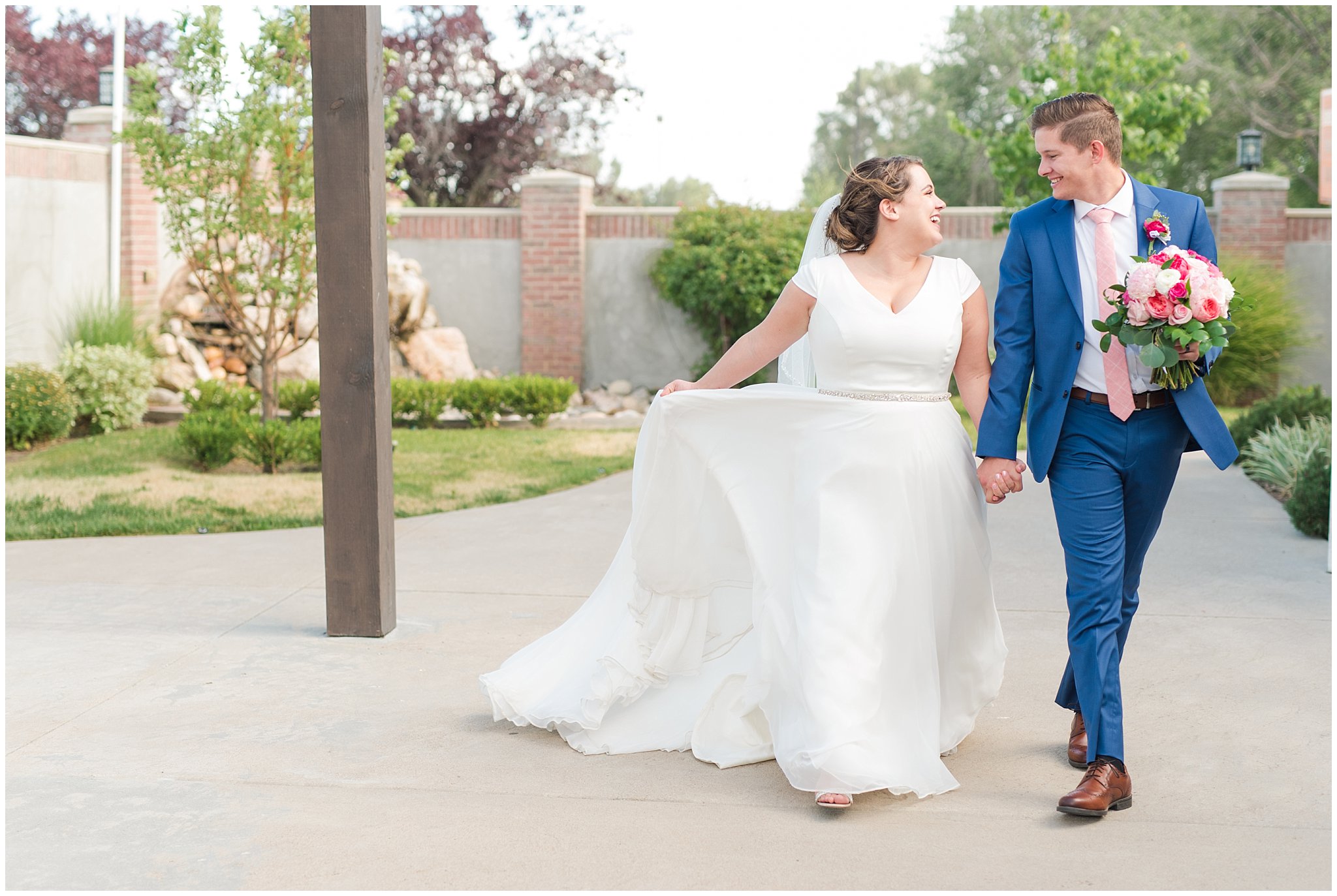 Bride and groom walking in courtyard wearing flowy dress and cornish blue suit | Talia Event Center Summer Wedding | Jessie and Dallin Photography