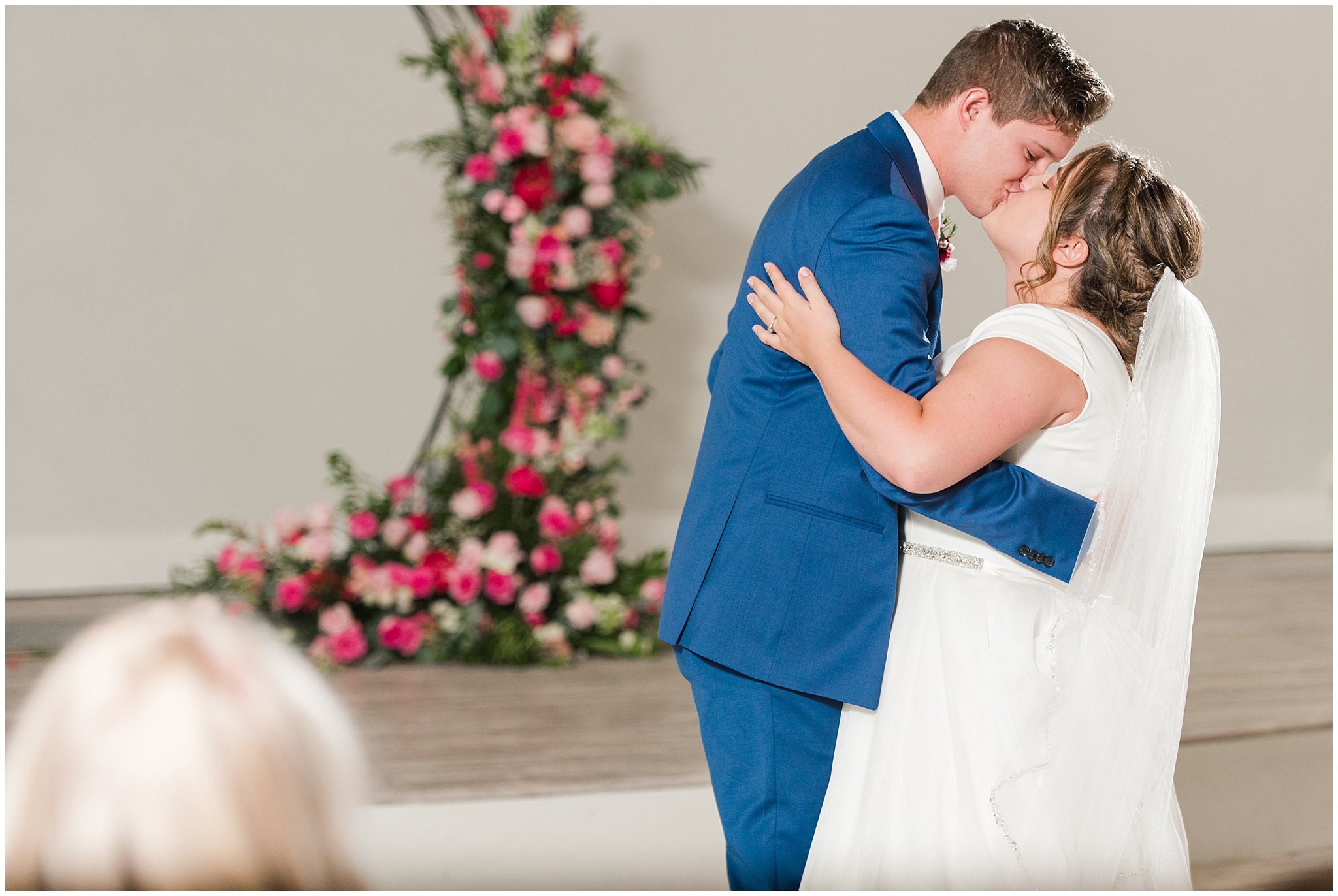 Bride and groom dance underneath chandelier with flowy dress and cornish blue suit | Talia Event Center Summer Wedding | Jessie and Dallin Photography