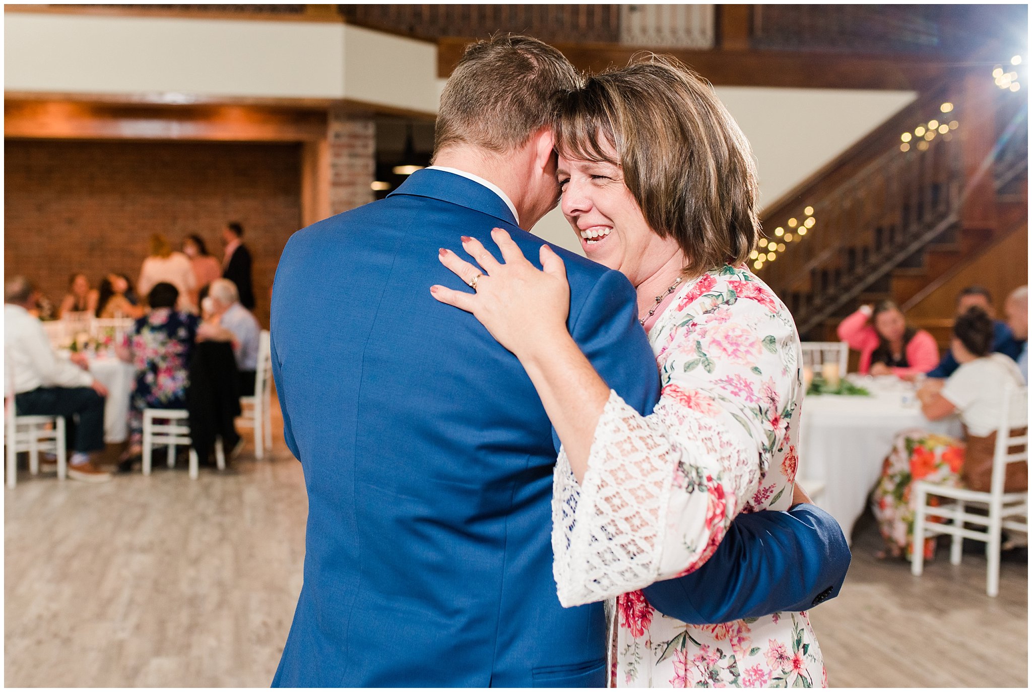 Emotional moments during mother son dance with floral arch in shades of pink | Talia Event Center Summer Wedding | Jessie and Dallin Photography