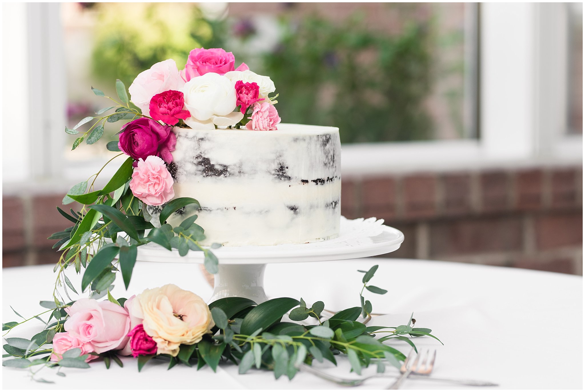 Cookies and cream cake in front of windows and covered with pink and white florals | Talia Event Center Summer Wedding | Jessie and Dallin Photography