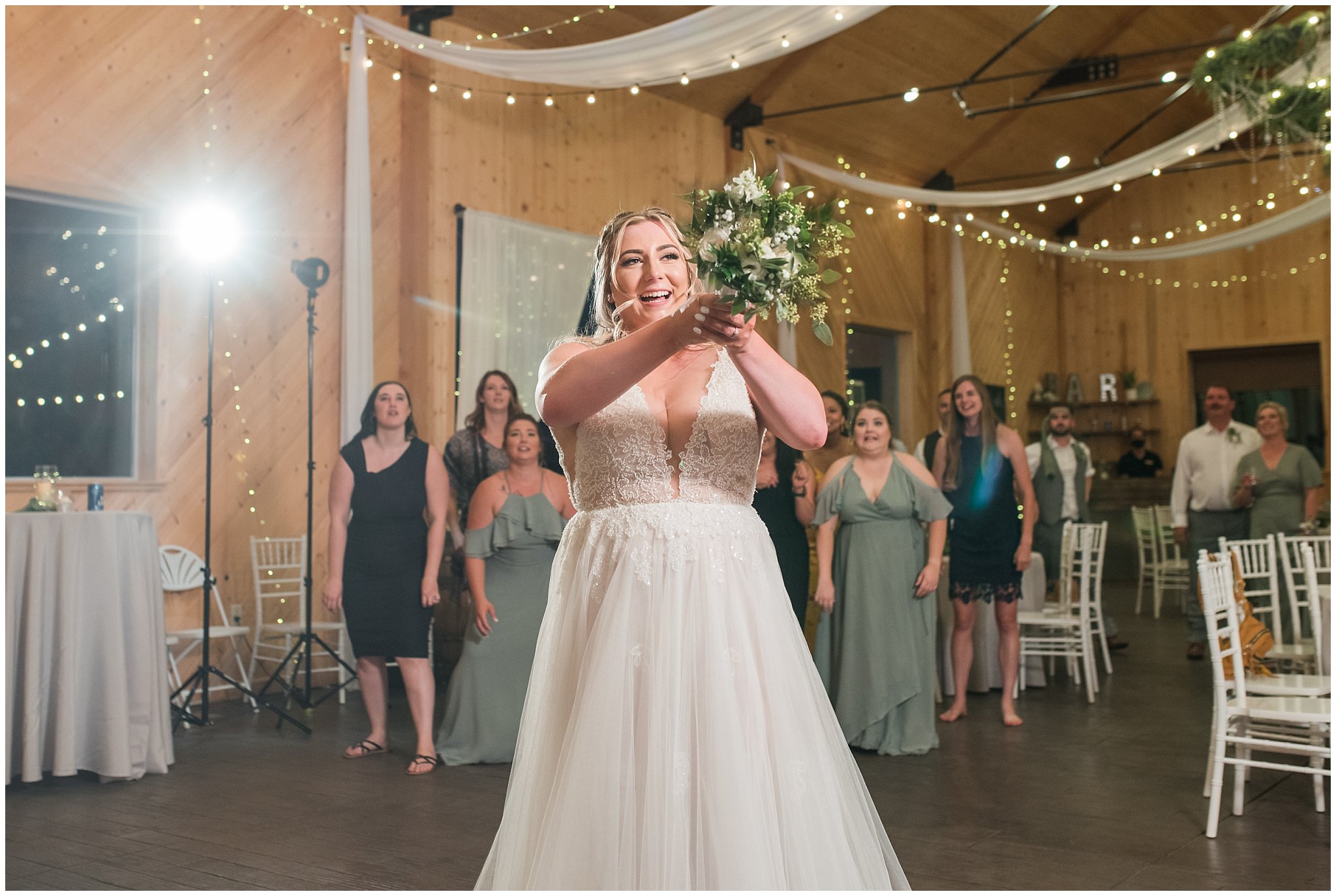 Bouquet toss in a barn during wedding reception | Sage Green and Gray Summer Wedding at Oak Hills | Jessie and Dallin Photography