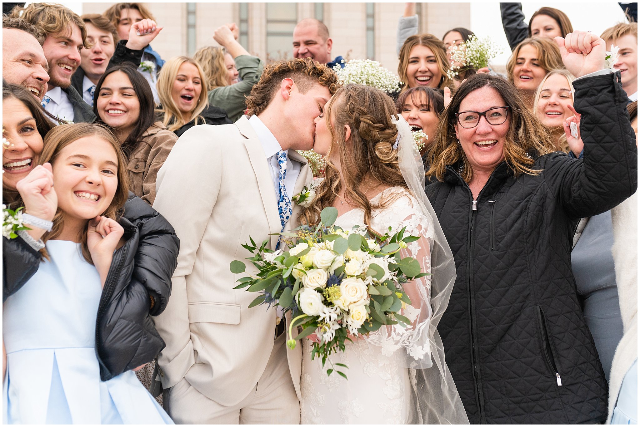 Bride and groom kiss surrounded by family and friends | Oquirrh Mountain Temple and Draper Day Barn Winter Wedding | Jessie and Dallin Photography