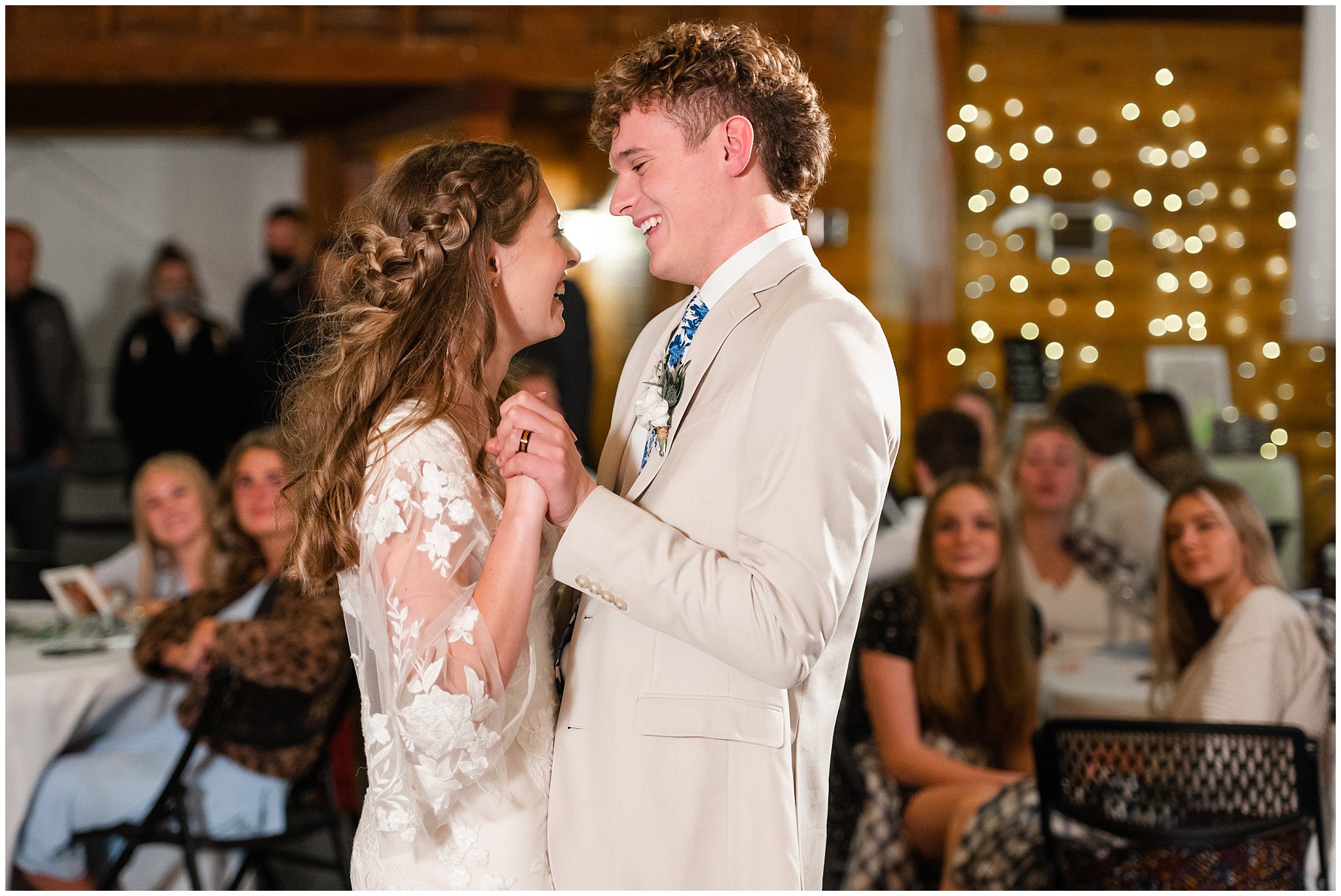 Bride and groom share first dance at their reception. Groom in cream colored suit with blue floral tie and bride in lace detailed wedding dress | Oquirrh Mountain Temple and Draper Day Barn Winter Wedding | Jessie and Dallin Photography