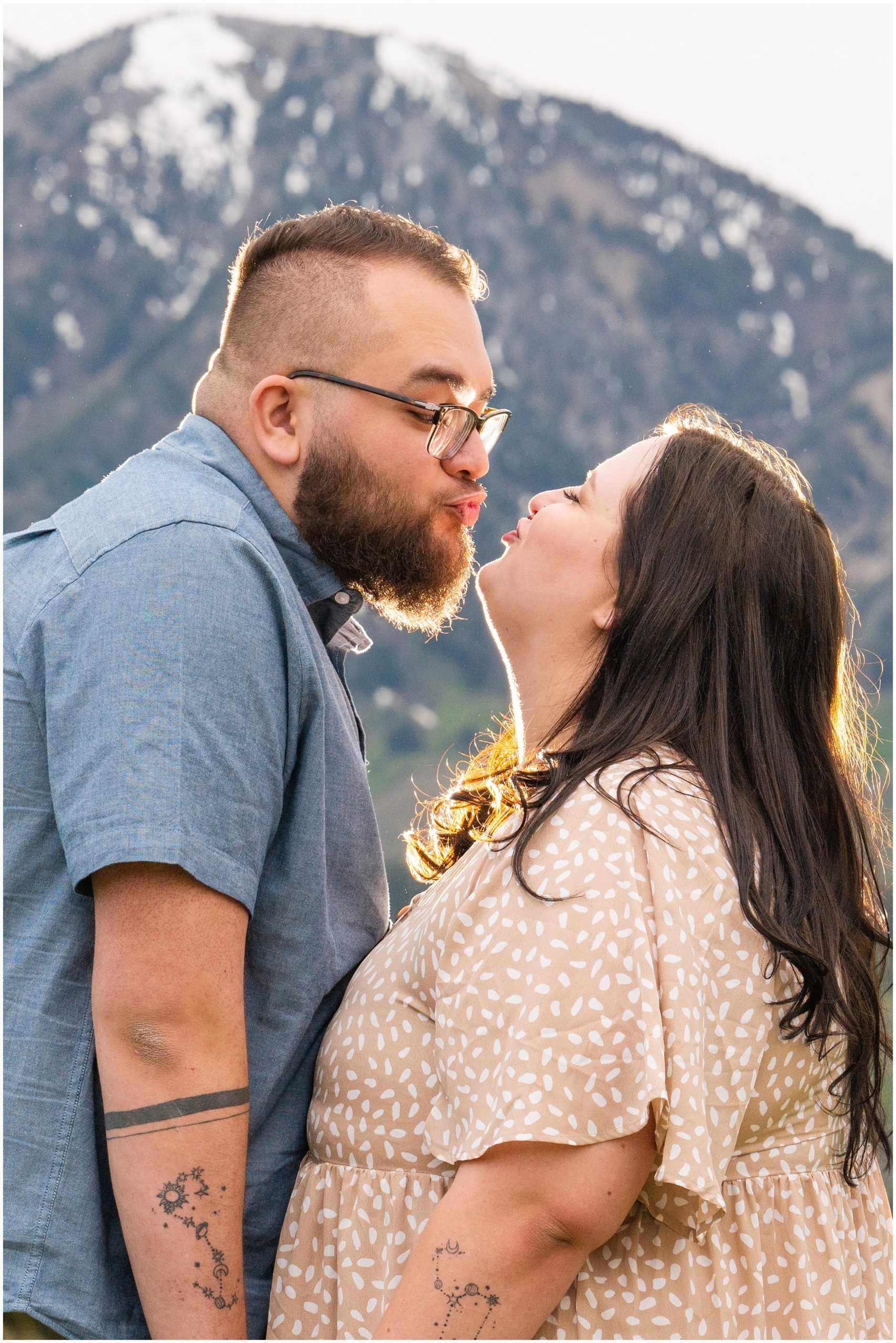 Couple during engagement session in yellow sunflower wildflowers surrounded by snowy mountain peaks | Ogden Valley Summer Engagement Session