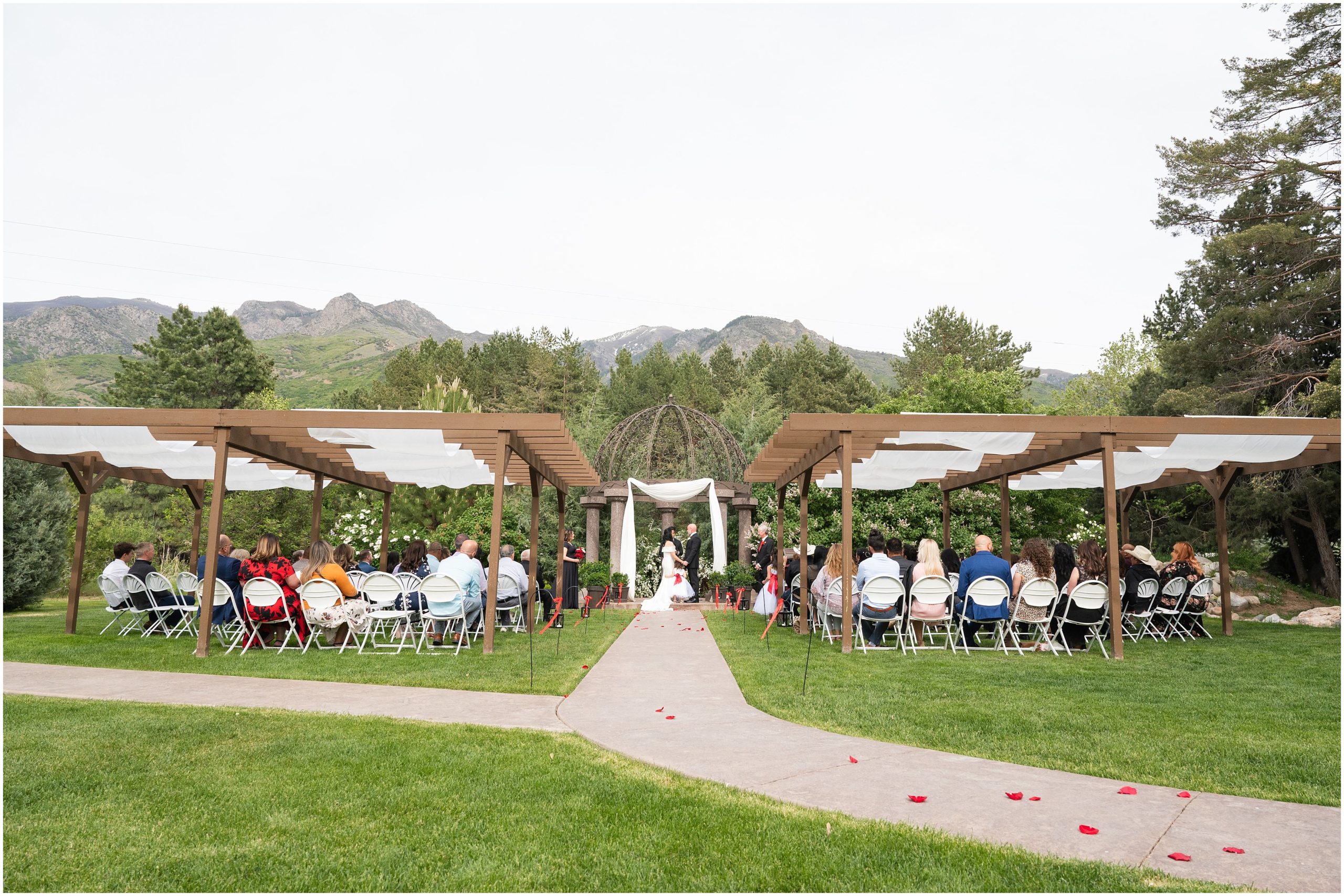 Wedding ceremony with Utah mountain backdrop and with red roses in aisle | Red and Black Oak Hills Utah Spring Wedding | Jessie and Dallin Photography