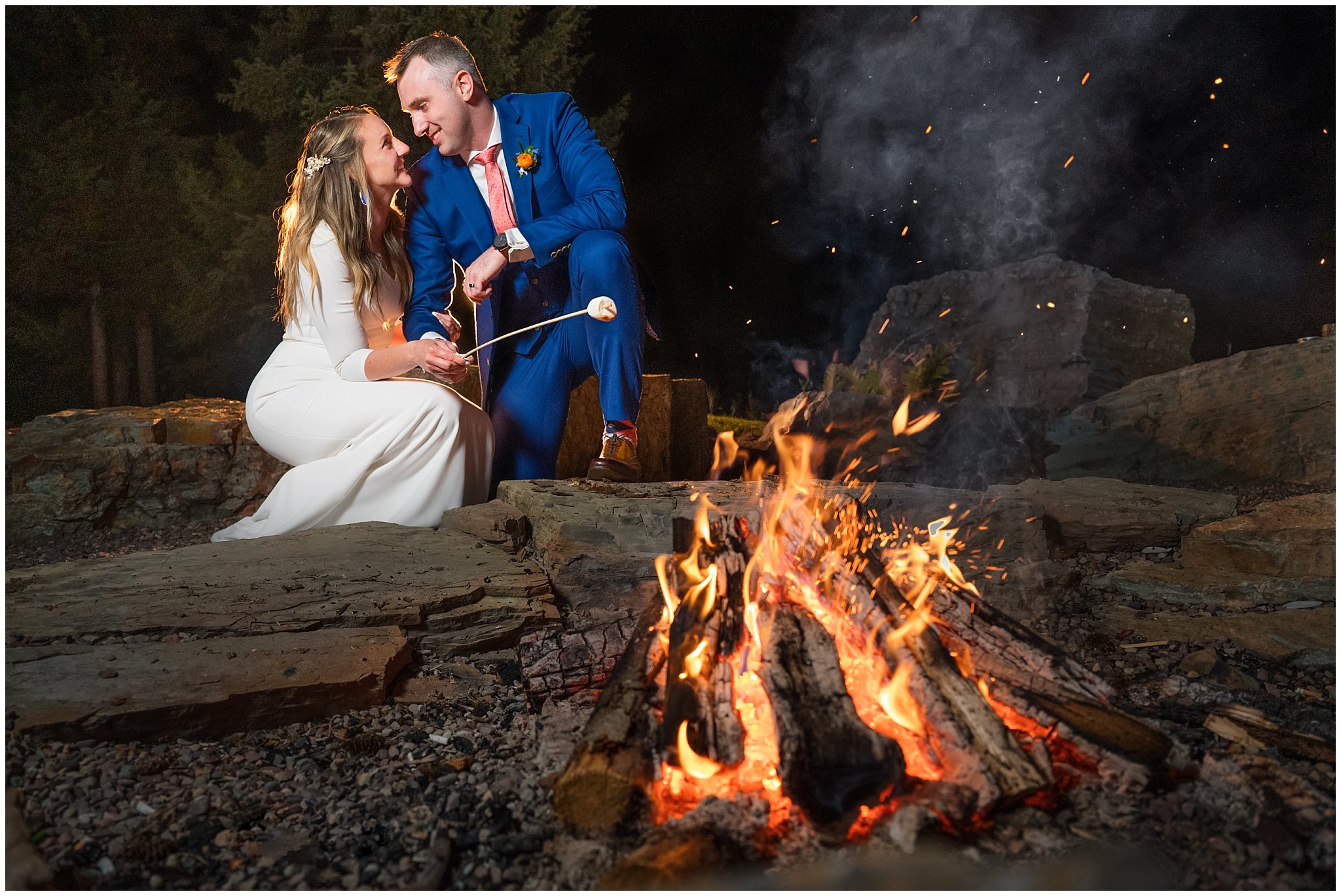 Bride and groom roasting smores around fire during wedding in the Montana forest | Mountainside Weddings Kalispell Montana Destination Wedding | Jessie and Dallin Photography