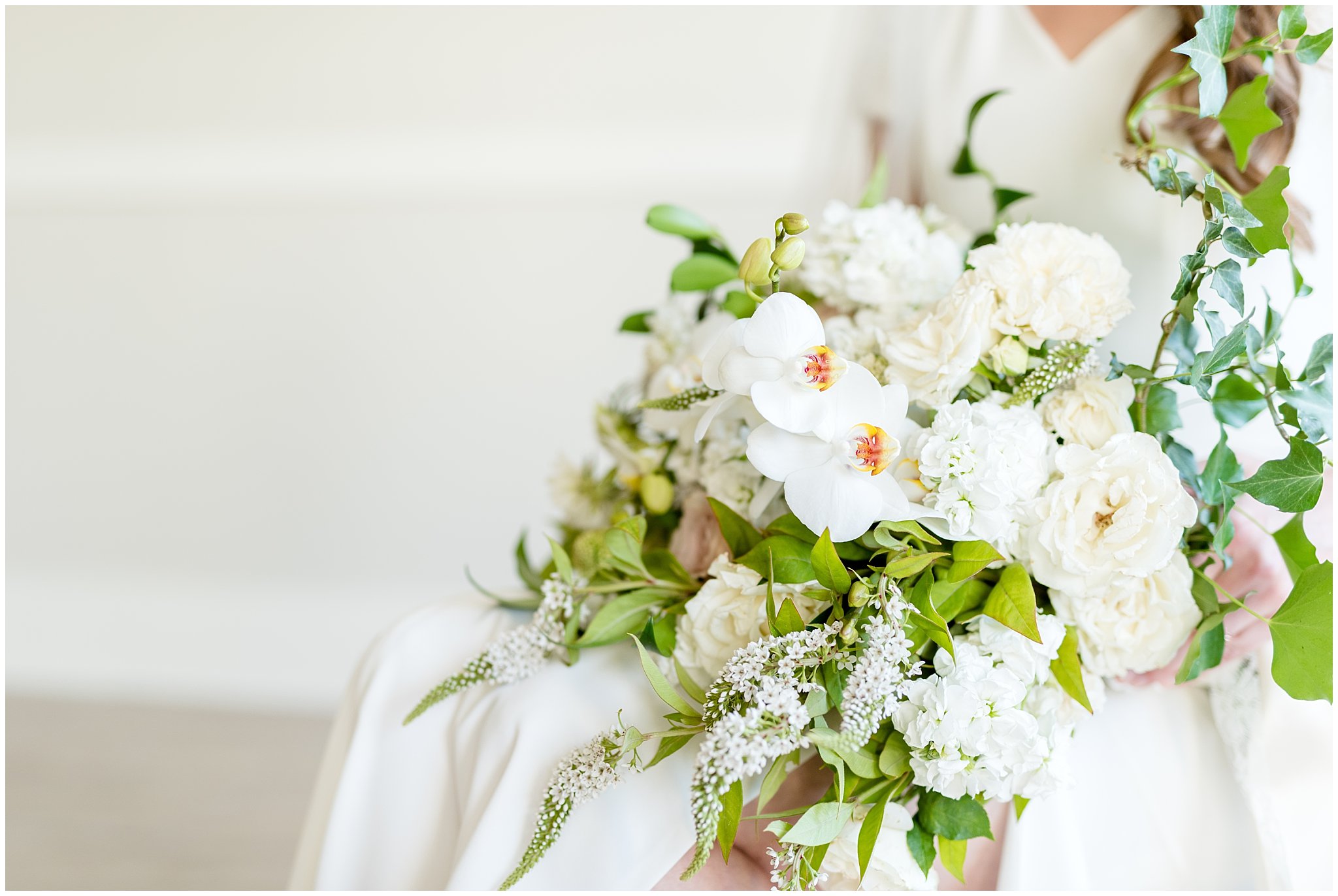 White and green wedding bouquet being held in bride's lap