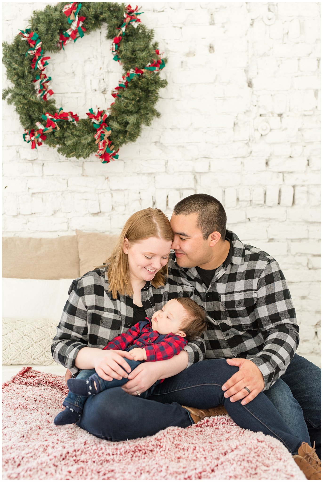 Parents snuggling baby on bed | Family Christmas session at the 5th floor | Utah Photographers | Jessie and Dallin Photography