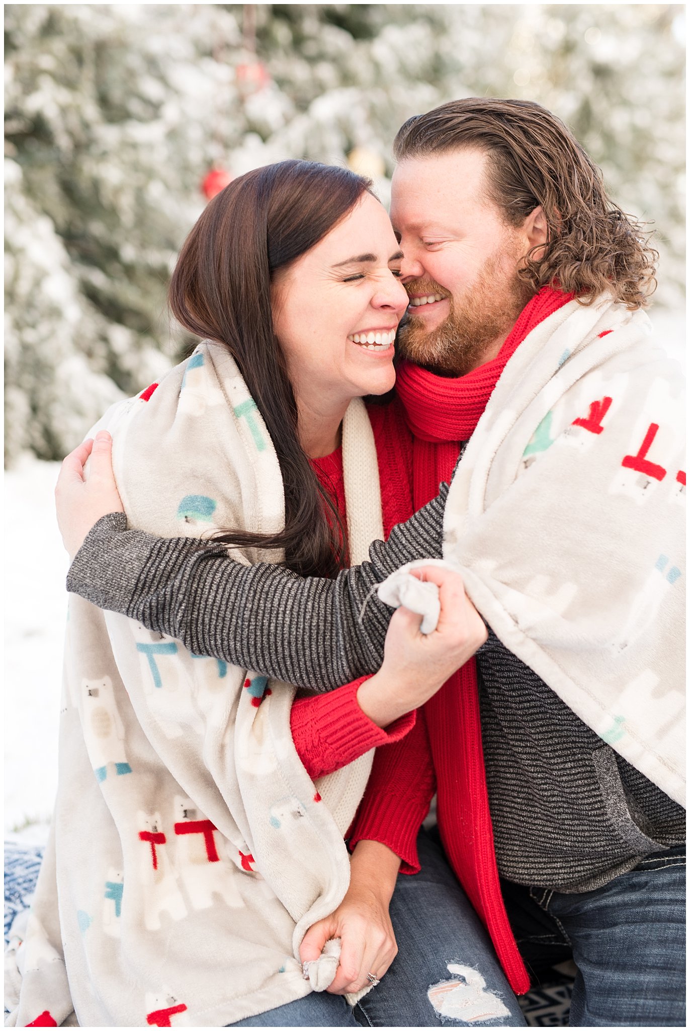 Couple cuddled up in the snow laughing | Utah Family Christmas Photoshoot | Oak Hills Reception and Event | Jessie and Dallin Photography