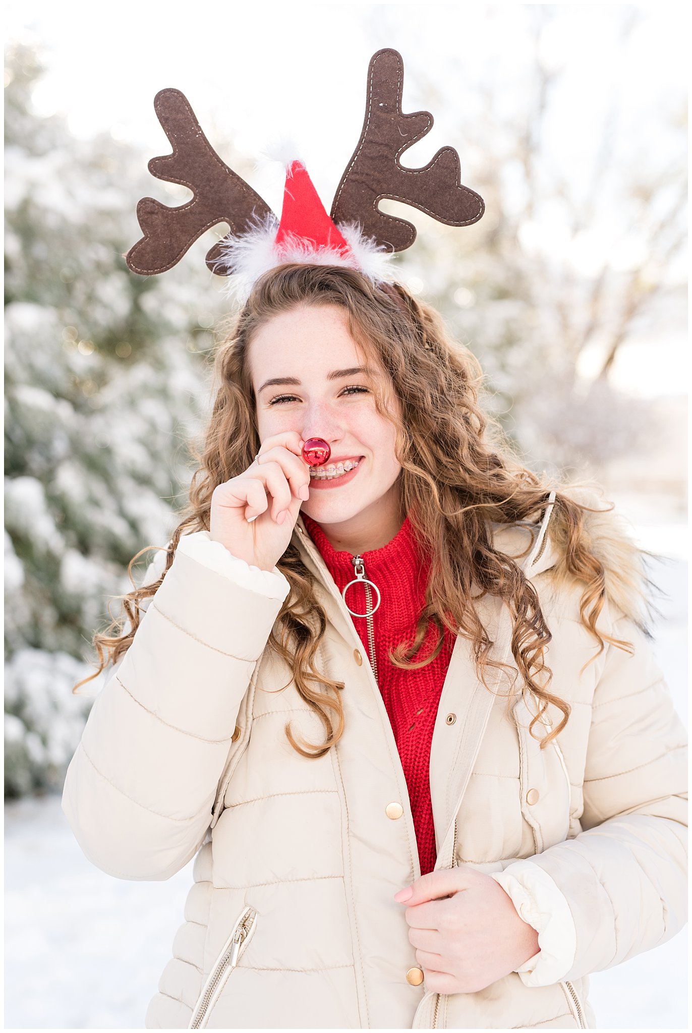 Teenage girl in rudolph nose and reindeer antlers in front of Christmas trees | Utah Family Christmas Photoshoot | Oak Hills Reception and Event | Jessie and Dallin Photography
