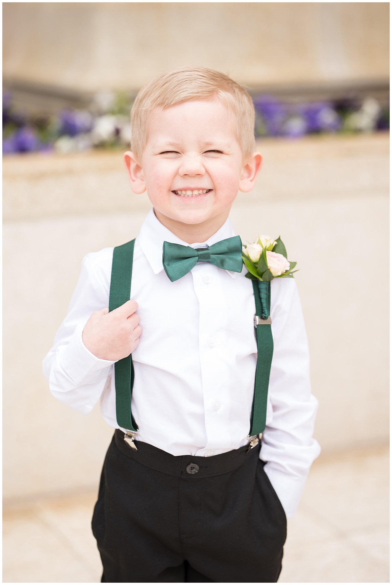 Ring bearer cheesy smile at the camera with emerald green suspenders and bowtie | Ogden Temple Winter Wedding | Emerald Green and Pink Wedding | Jessie and Dallin Photography