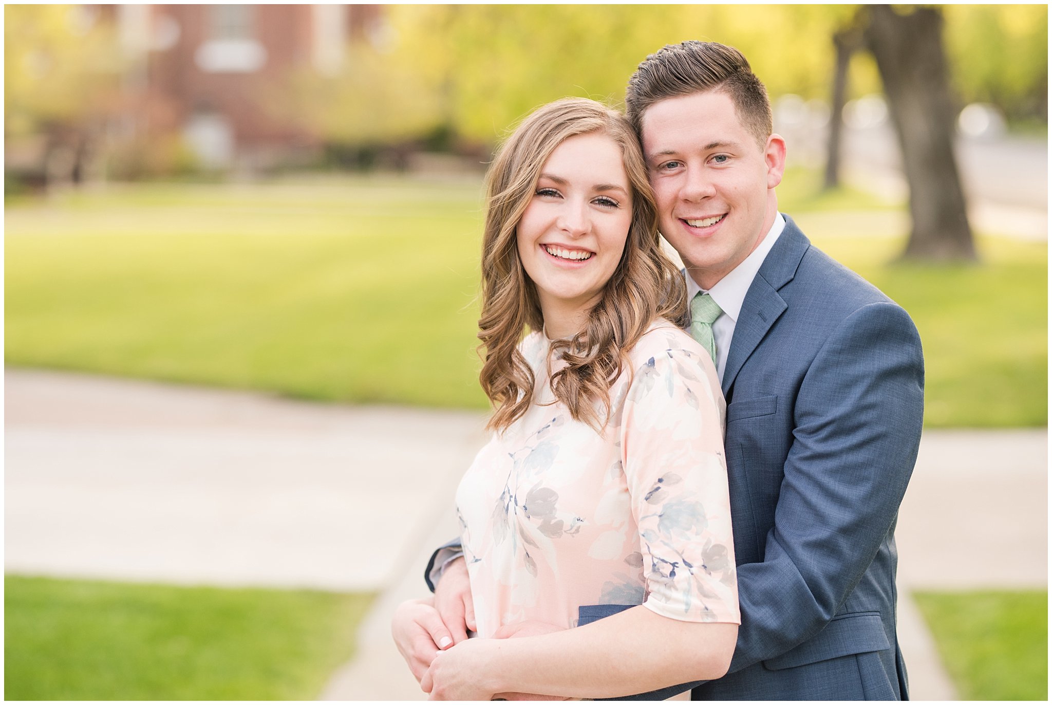 Couple dressed up in blue suit and blush dress surrounded by the city and trees in the spring | Downtown Logan and Wellsville Mountain Engagement | Jessie and Dallin Photography