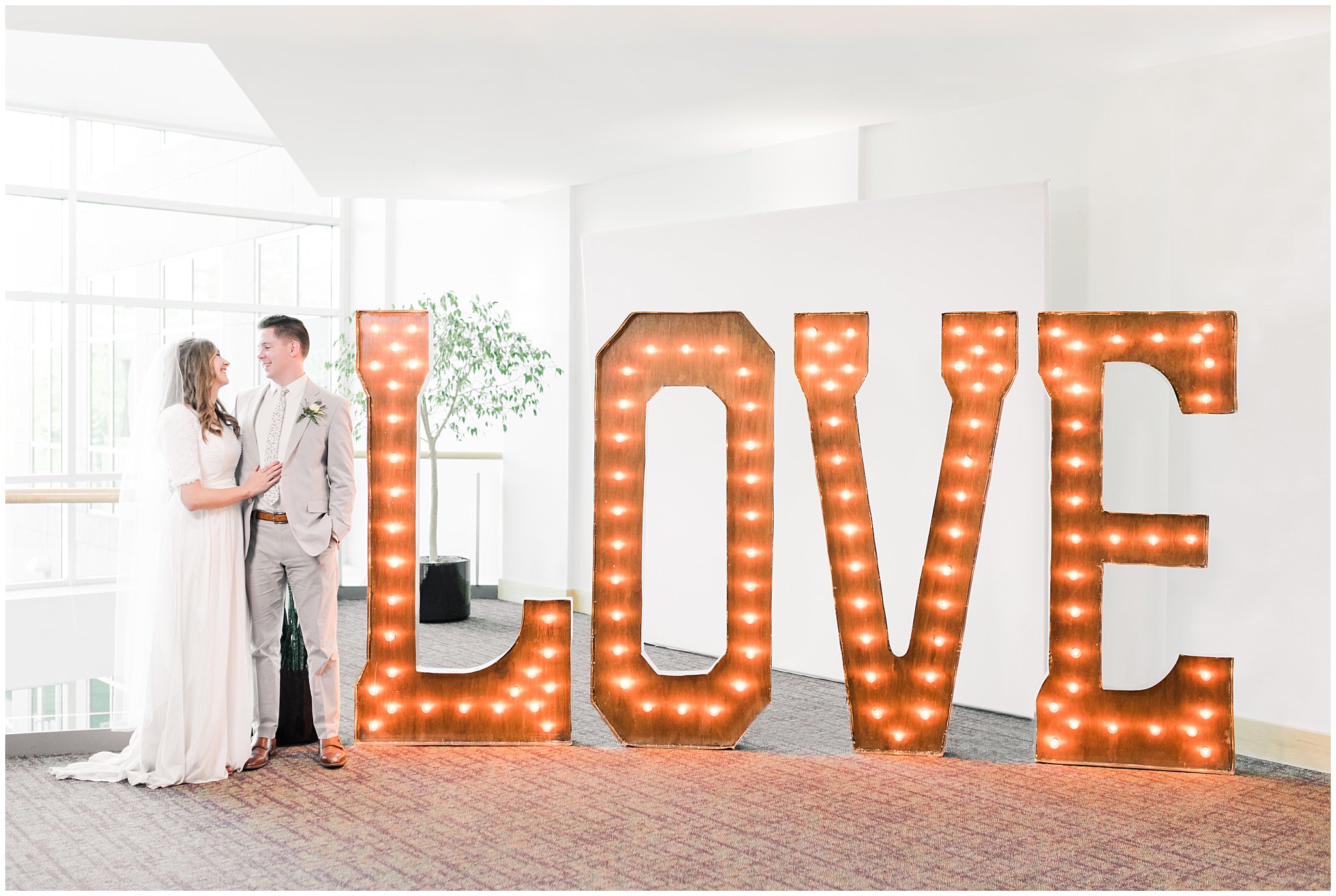 Bride and Groom in front of LOVE sign reception decor | Salt Lake Temple Wedding and Clearfield City Hall Reception | Utah Wedding Photographers | Jessie and Dallin Photography