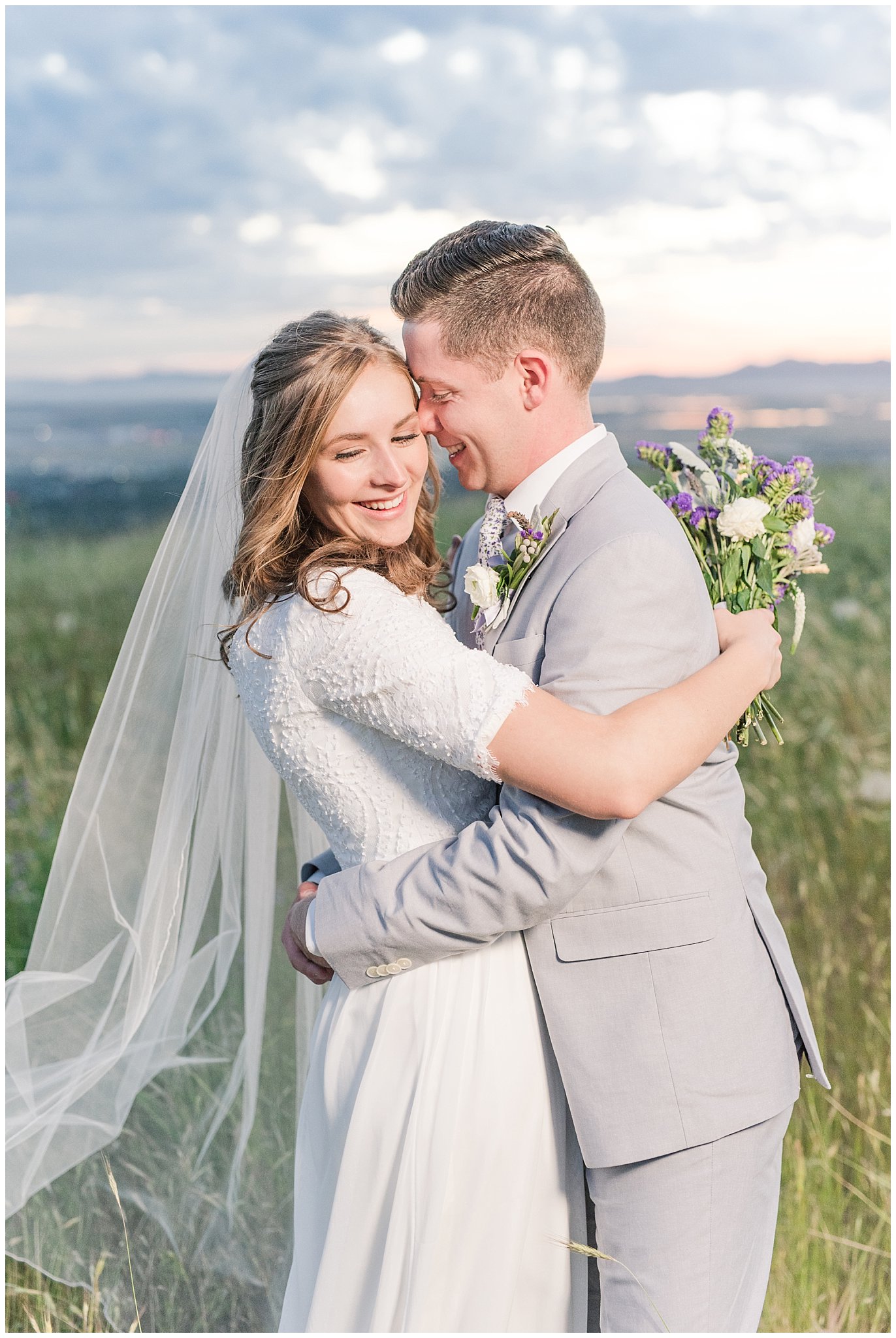 Bride and groom at sunset overlooking Salt Lake City | Wearing elegant, simple dress with veil and grey suit with lavender florals | Elegant formal session at the Salt Lake Temple and Ensign Peak Formal Session | Jessie and Dallin Photography