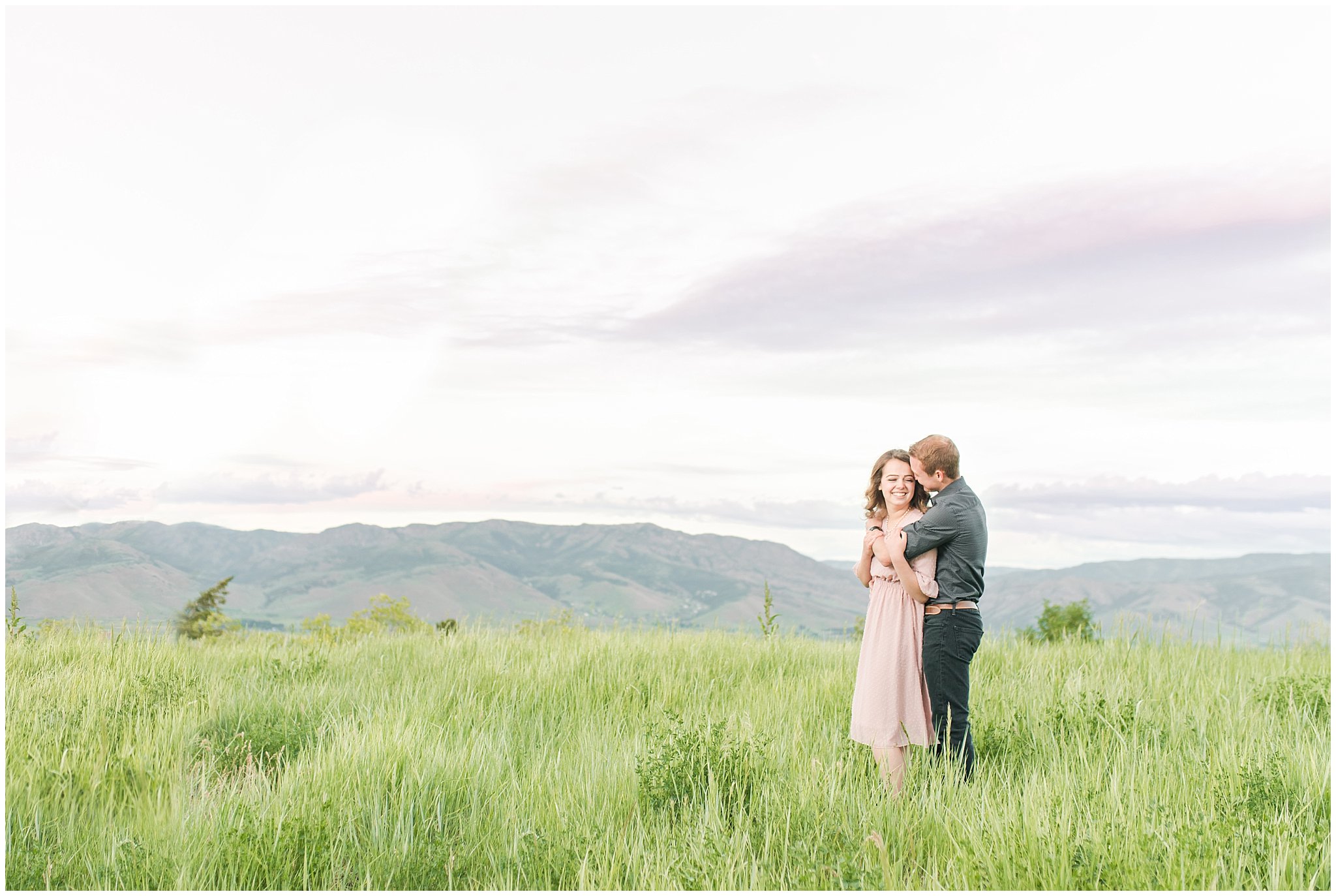 Couple in blush dress and grey and black buttoned shirt in front of a mountain view | Trapper's Loop Mountain Engagement | Utah Mountain Engagement Session | Jessie and Dallin Photography