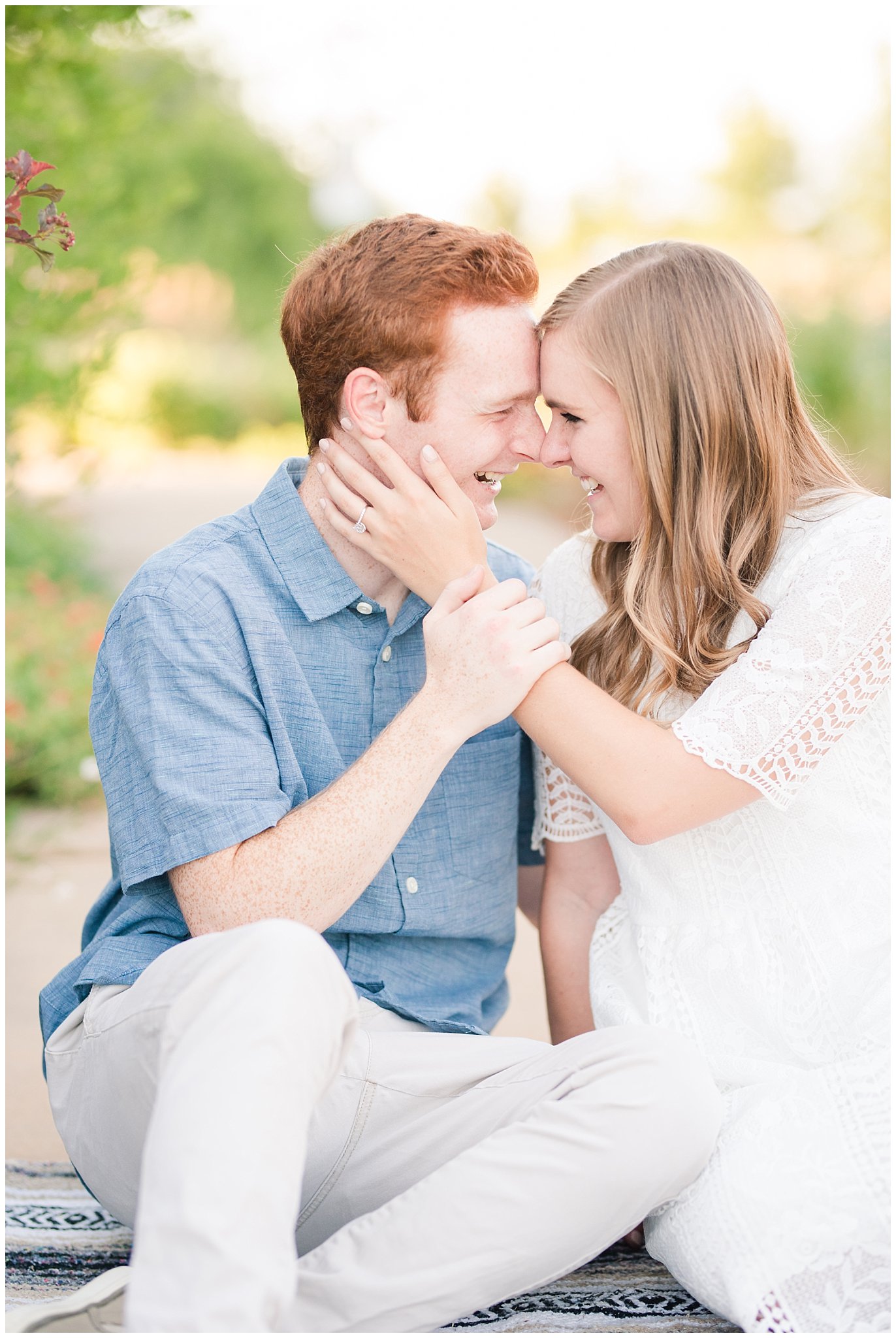 Couple wearing a white lace dress and light blue shirt during candid engagement photos in a Utah garden with flowers and a pond | Kaysville Botanical Garden Engagement | Utah Engagement | Jessie and Dallin Photography