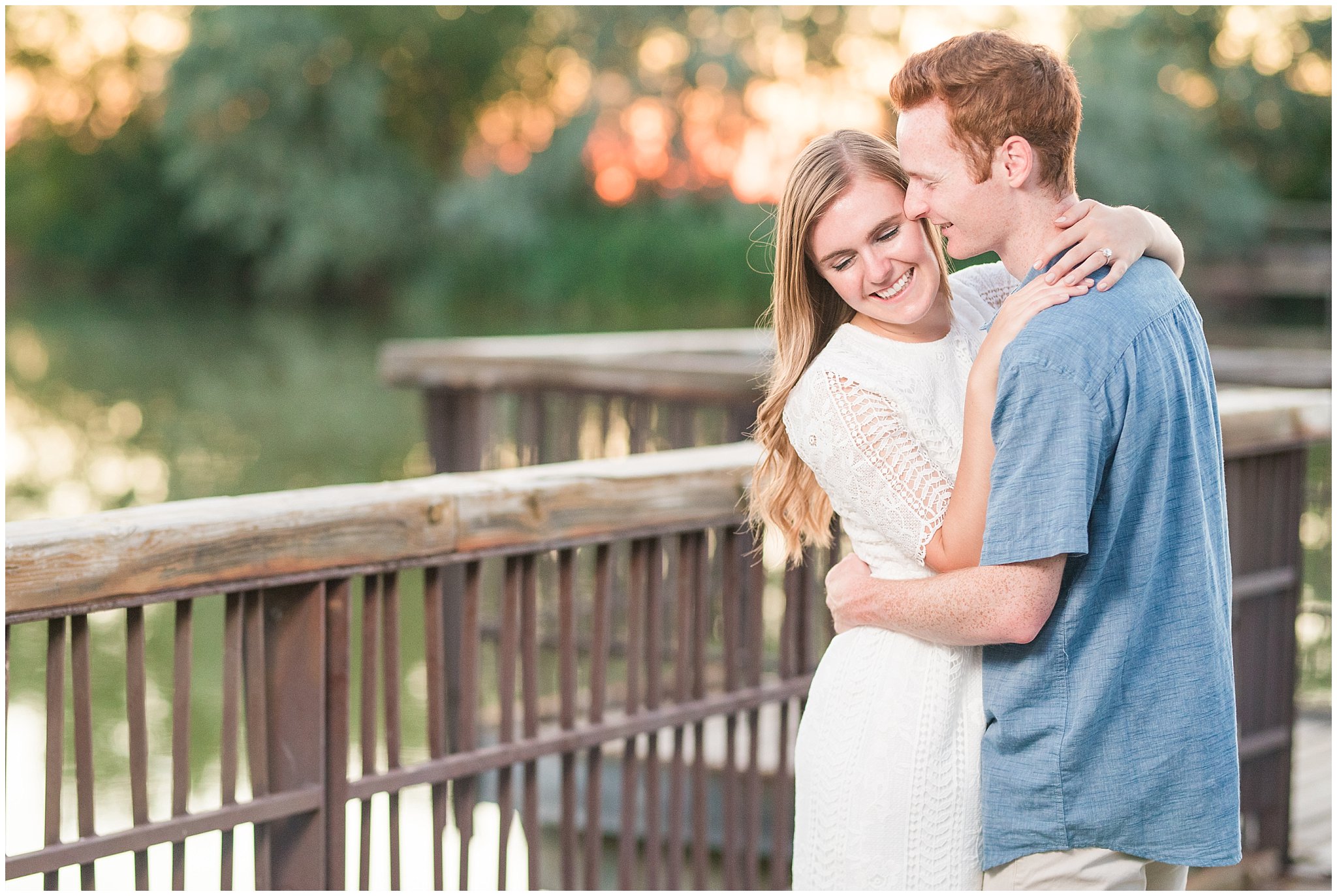 Couple wearing a white lace dress and light blue shirt during candid engagement photos in at a pond with a dock | Kaysville Botanical Garden Engagement | Utah Engagement | Jessie and Dallin Photography