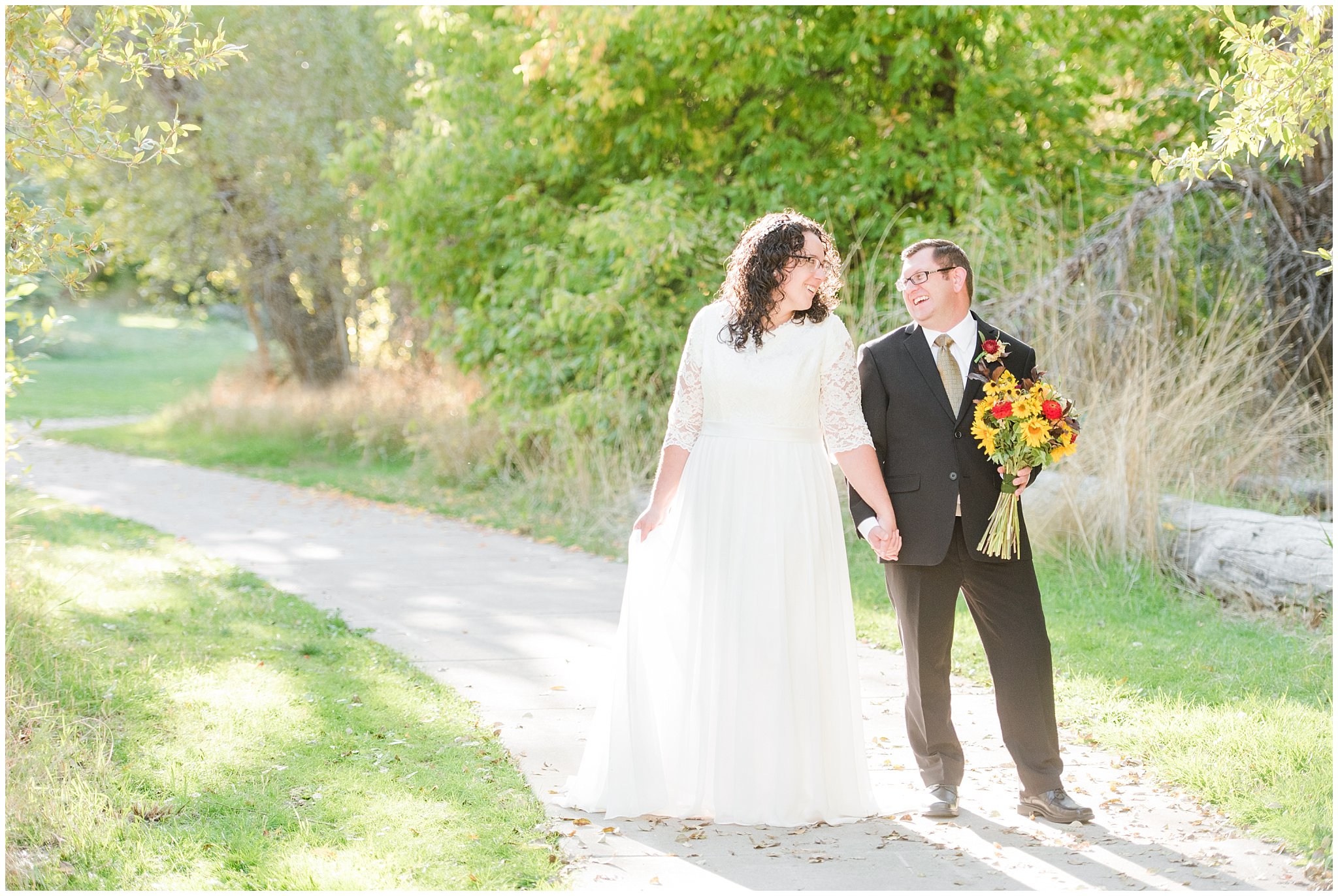 Groom in black suit and gold tie, bride in simple lace sleeve wedding dress with fall bouquet at Denzil Stewart Nature Park | Logan Temple Fall Formal Session | Jessie and Dallin Photography