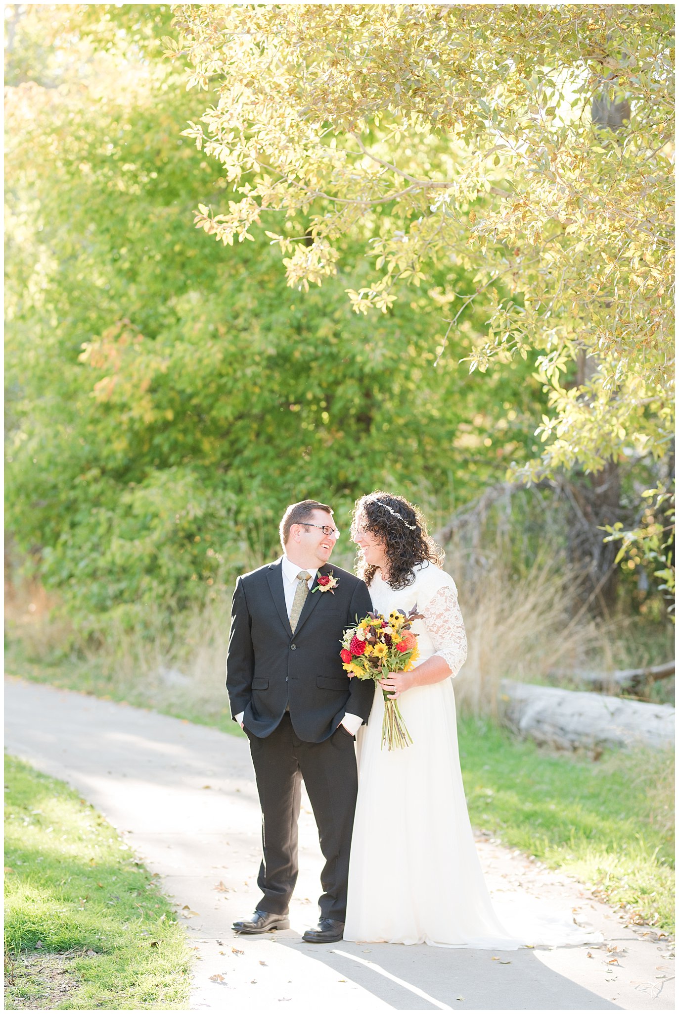 Groom in black suit and gold tie, bride in simple lace sleeve wedding dress with fall bouquet at Denzil Stewart Nature Park | Logan Temple Fall Formal Session | Jessie and Dallin Photography