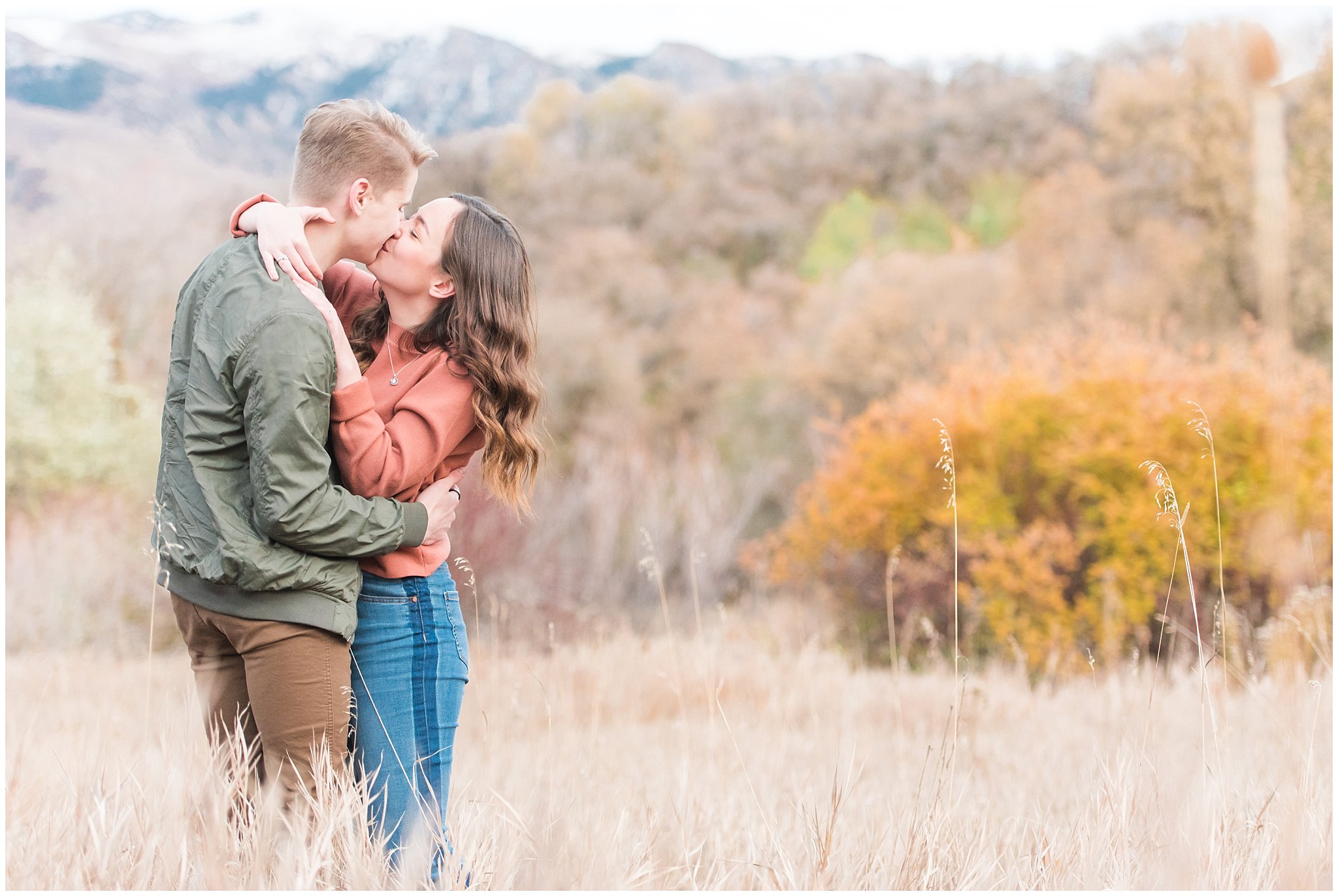 Couple dressed in fall colored sweater, jacket, jeans and boots with snowy mountain views | Kays Creek Parkway Fall Engagement Session | Utah Fall Engagement | Jessie and Dallin Photography