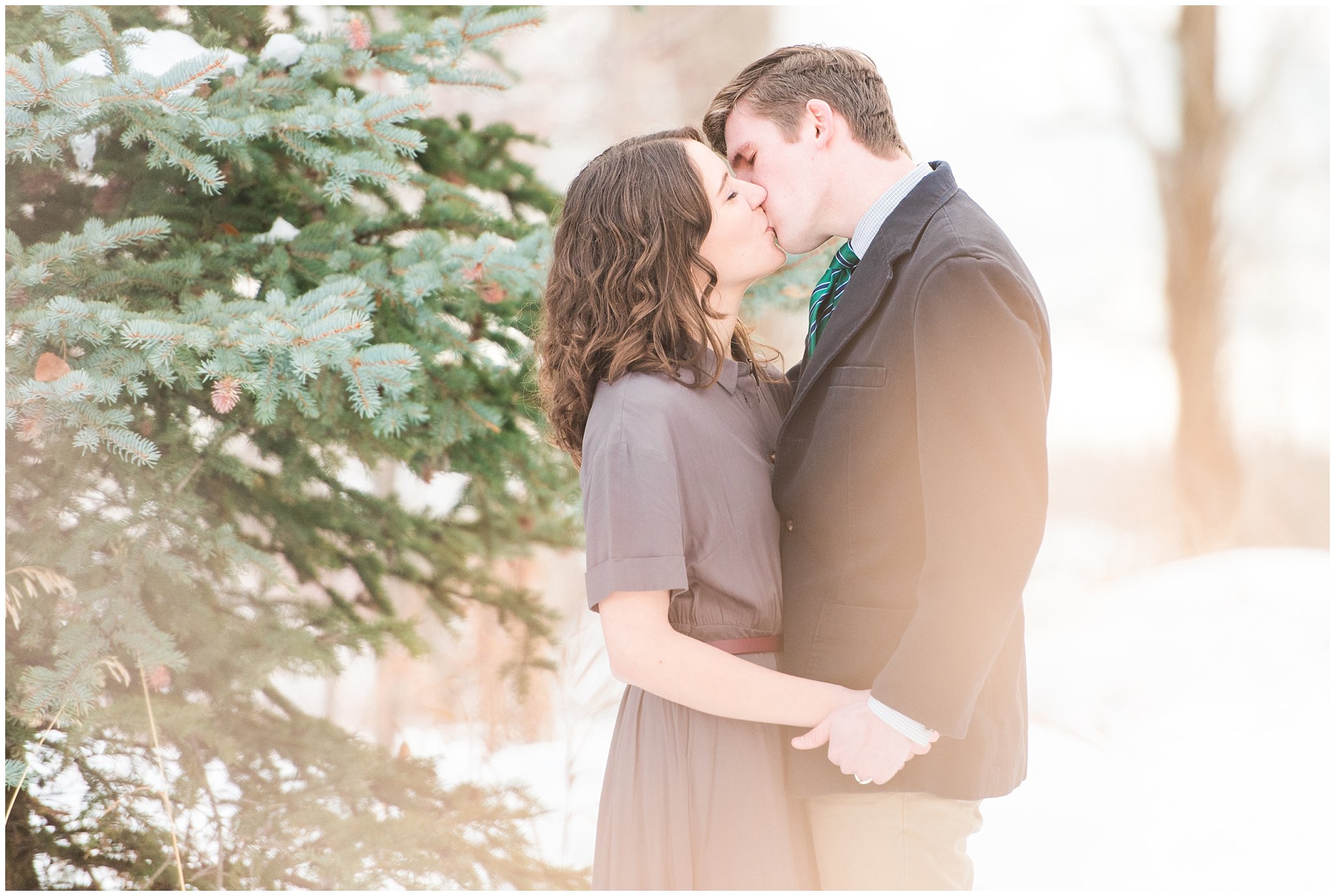 Snowy engagement session with pine trees and couple dressed up in grey dress and navy sport coat in the mountains | Snowbasin Winter Engagement Session