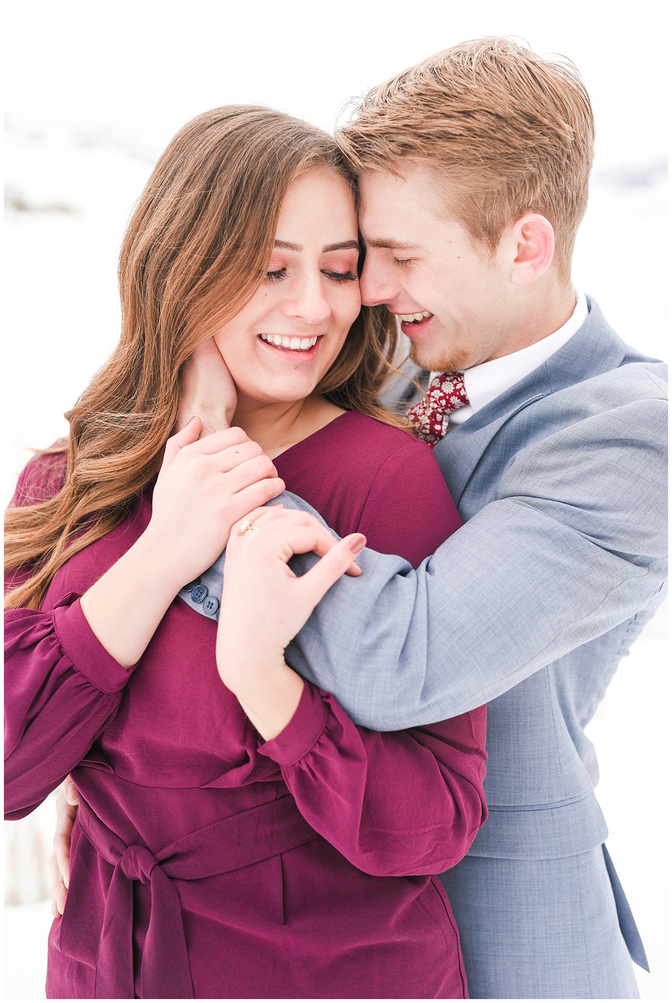 Couple dressed up in wine colored dress and light blue suit in the snowy Utah mountains | Mountain Green Winter Engagement | Jessie and Dallin Photography